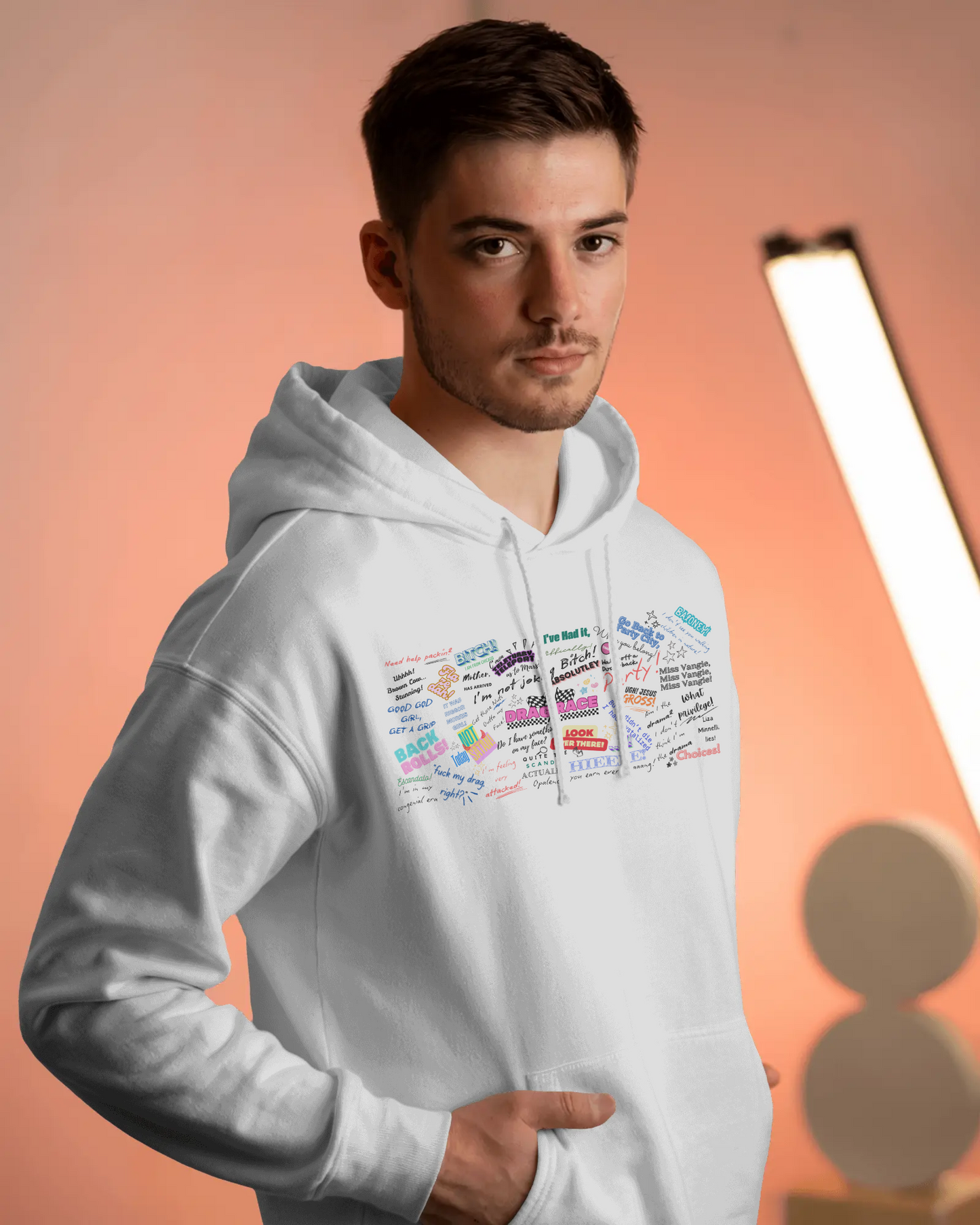 Man wearing a white hoodie with colorful text design on an orange background Drag race, Rupaul, Rupaul's Drag Race UK, LGBT, Queer Culture, Gay, Drag Queen