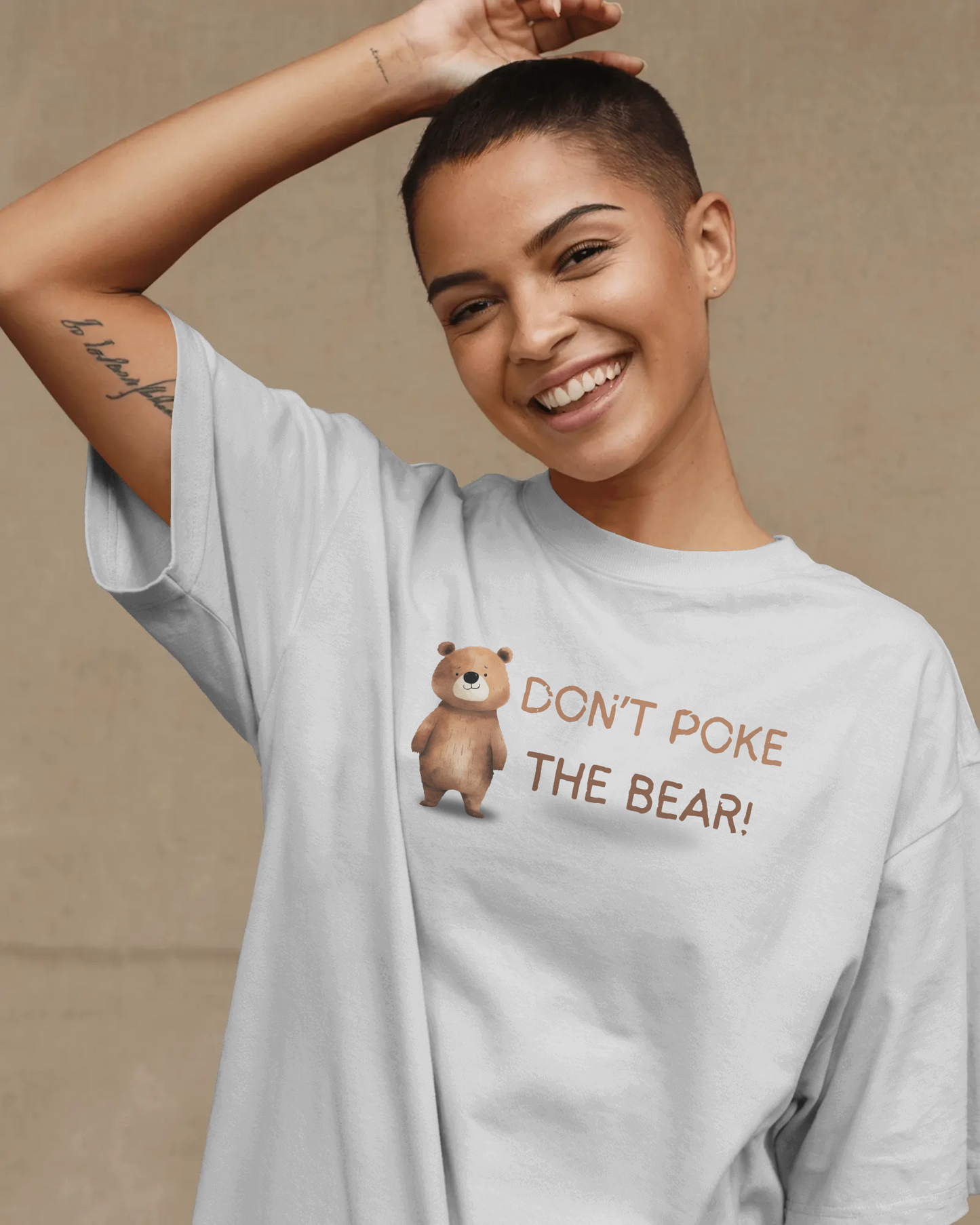 Person wearing a light gray t-shirt with a bear graphic and text on a beige background