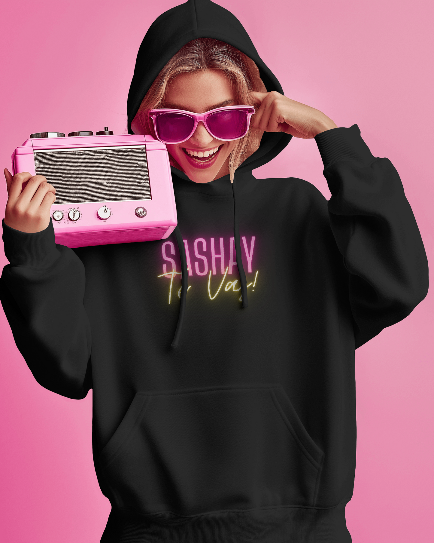 Person wearing a black hoodie with 'SASHAY' text, holding a pink vintage radio against a pink background Drag Race Espana, Drag Race Spain, Rupaul's drag race, Drag queens, LGBT, Queer culture