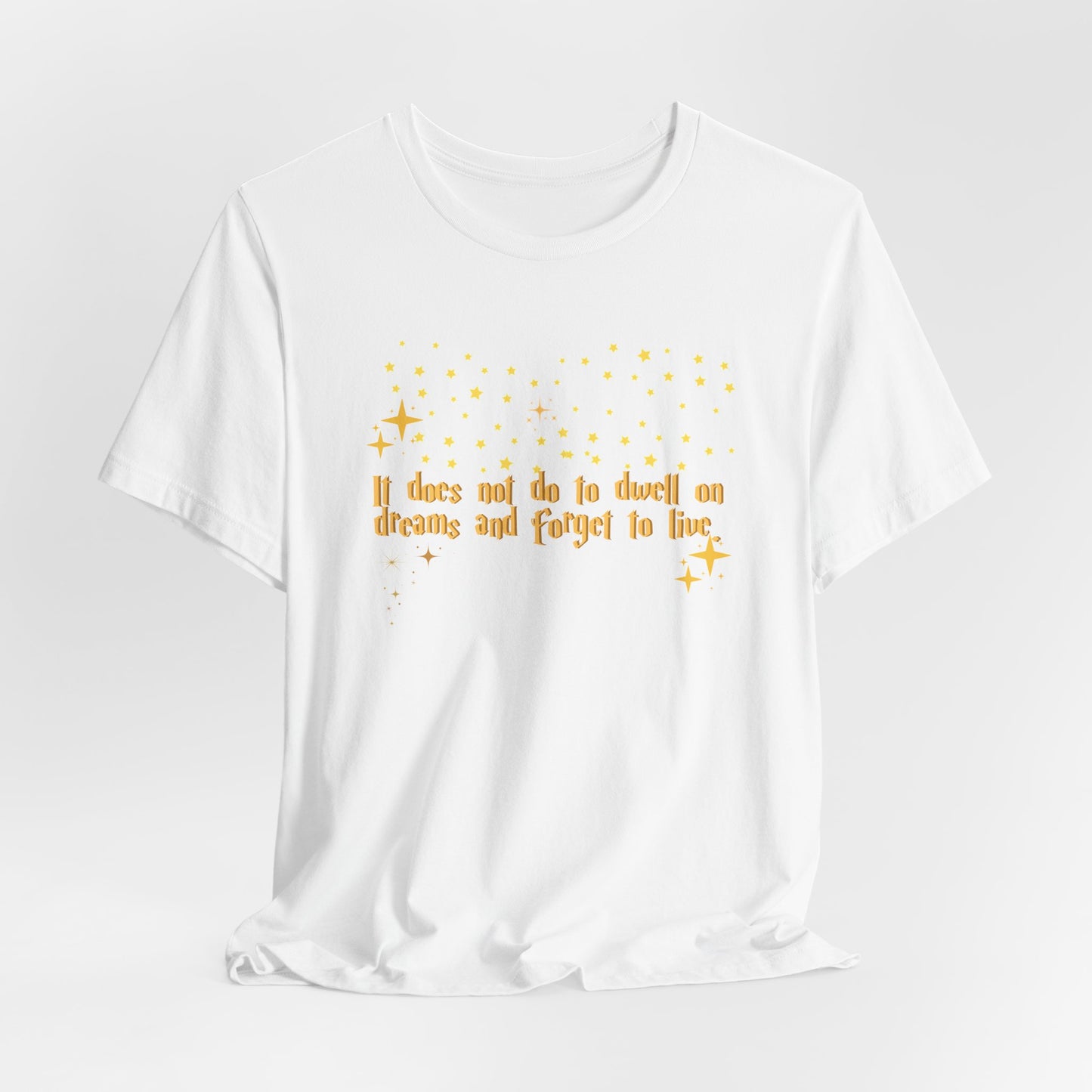 White t-shirt with yellow text and star graphics on a white background Dumbledore quote.