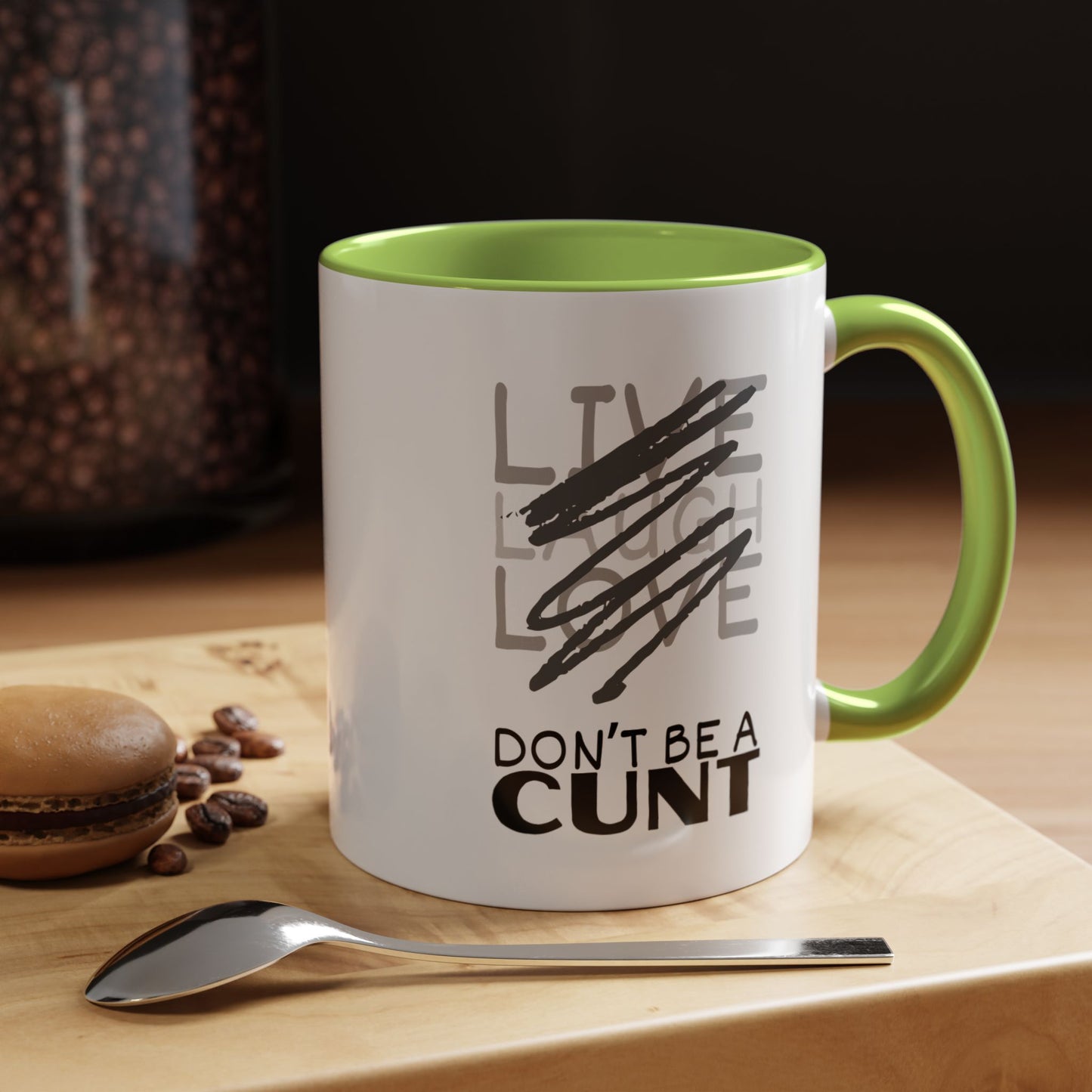 Mug with text on a wooden surface with coffee beans and a spoon