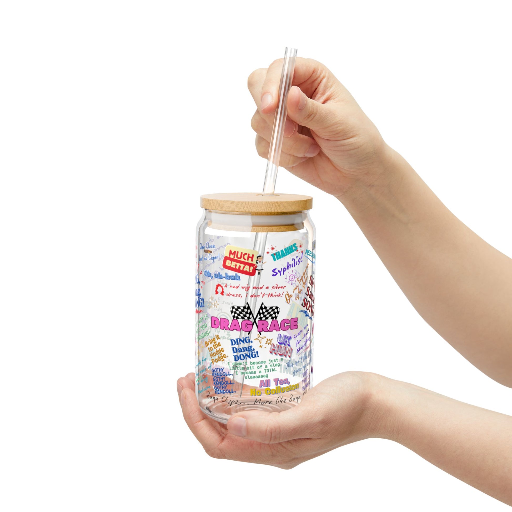 Glass tumbler with a wooden lid and colorful text design held by a hand on a white background Features iconic Quotes from your favorite Drag Race UK  Drag Queens.