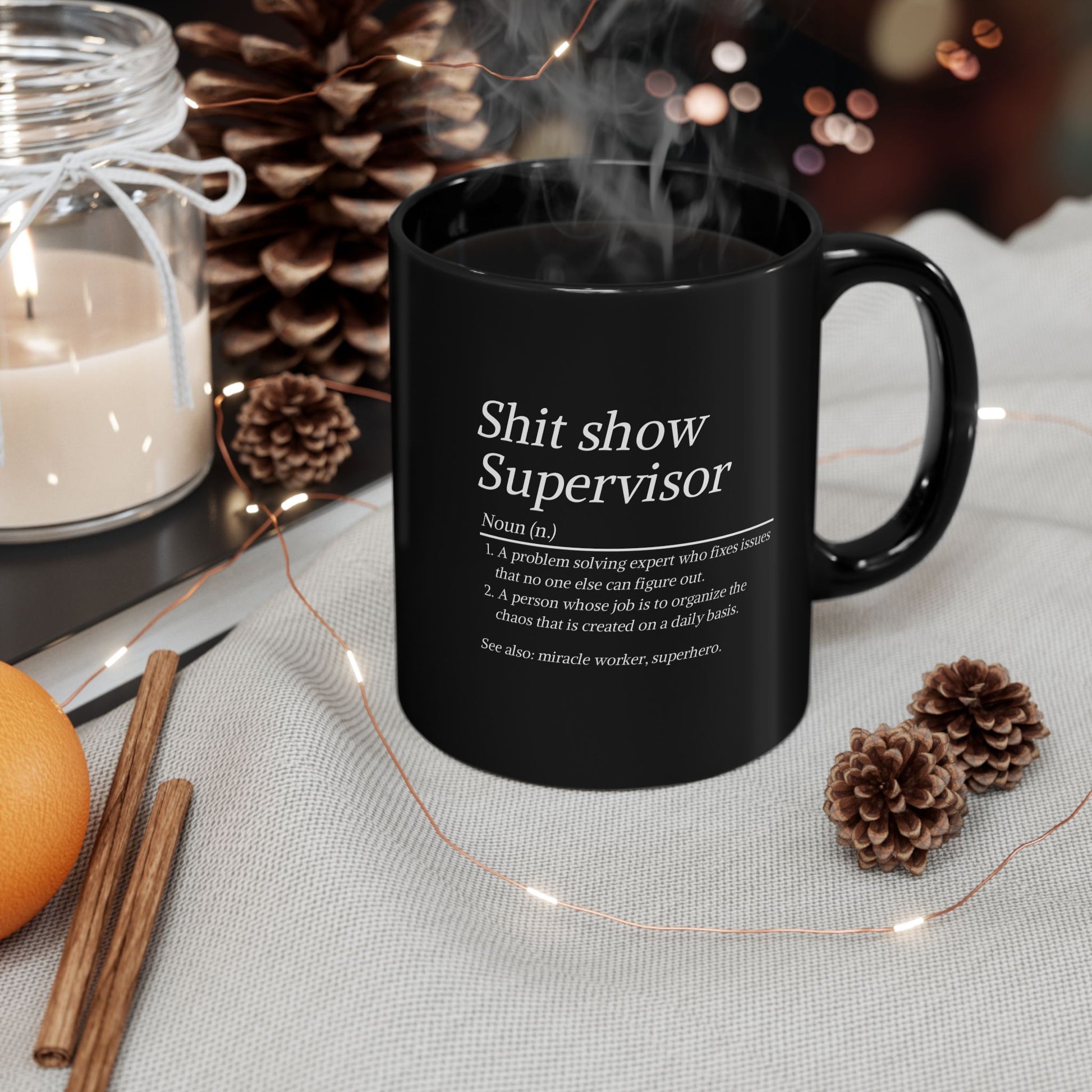 Black mug with text on a table with decorative items
