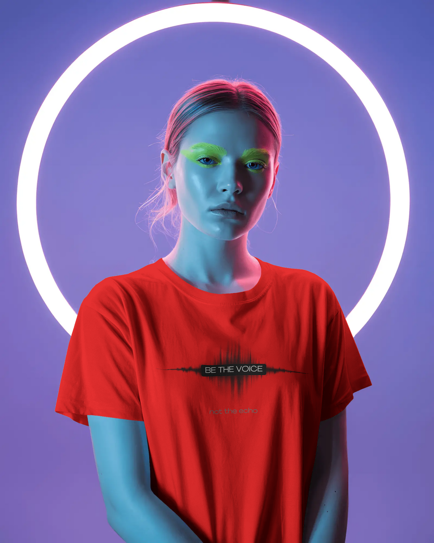 Person wearing a red t-shirt with a logo and text, standing against a purple background with a neon light circle.