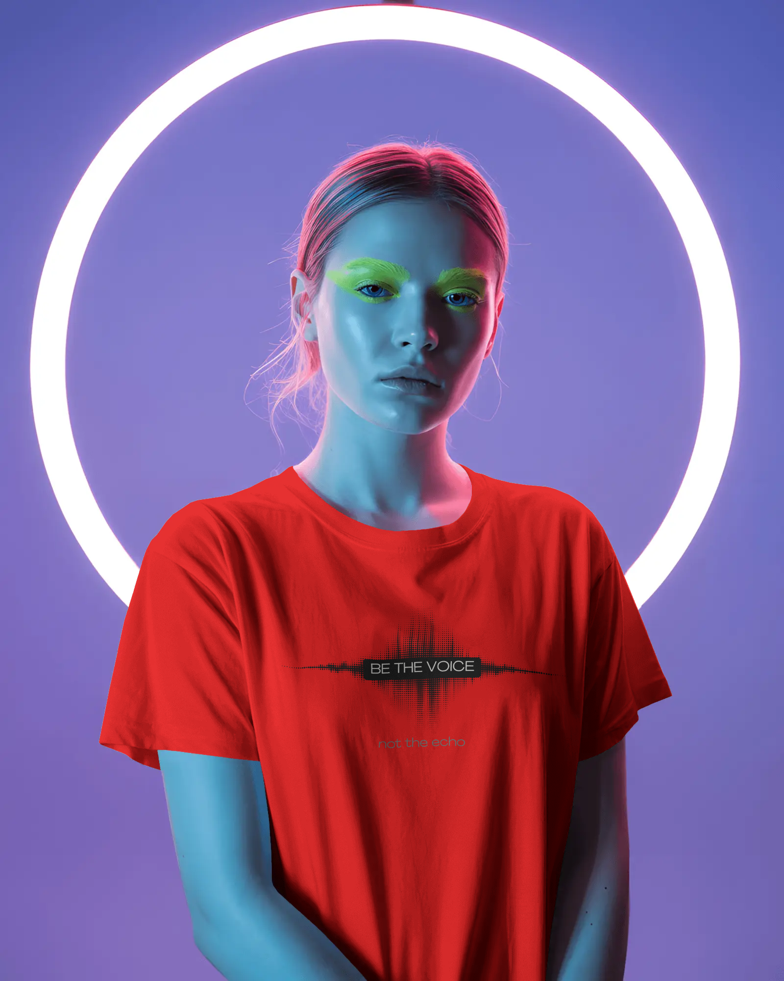 Person wearing a red t-shirt with a logo and text, standing against a purple background with a neon light circle.