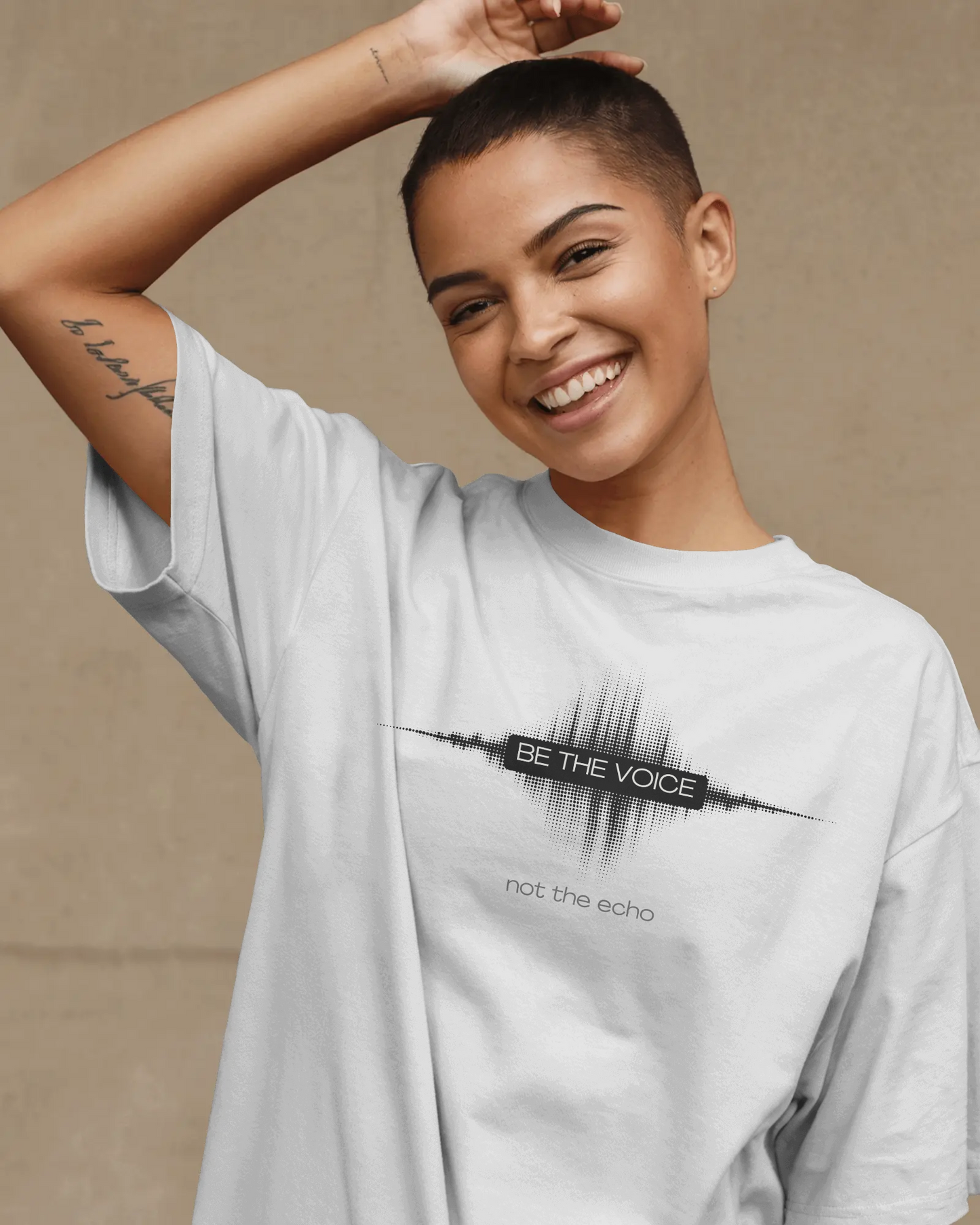 Person wearing a white t-shirt with a motivational quote on a beige background   Be the Voice, not the echo