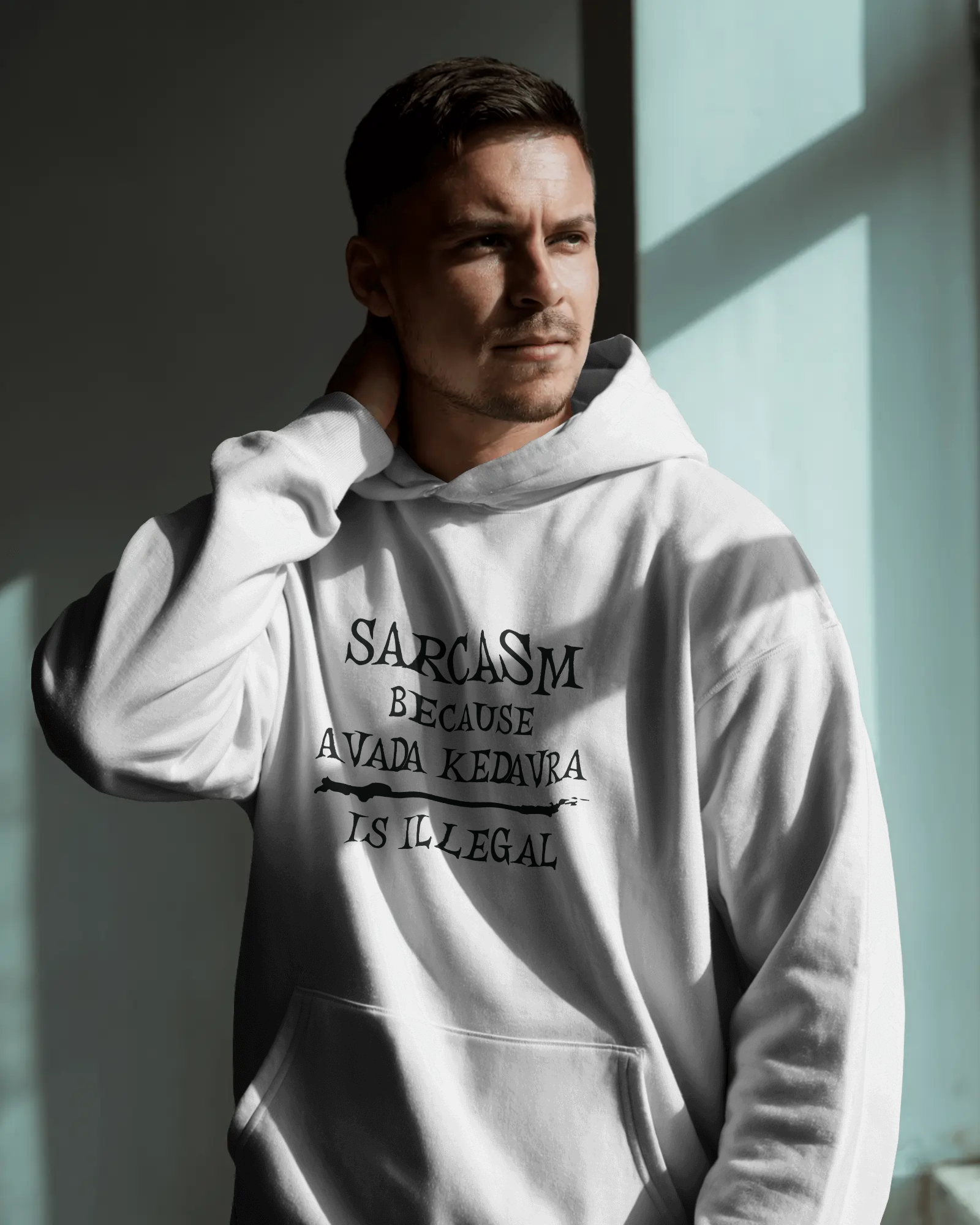 Man wearing a white hoodie with text, standing against a light-colored wall.  Sarcasm, Sarcastic Humor, Harry Potter, potterhead, avada kedavra