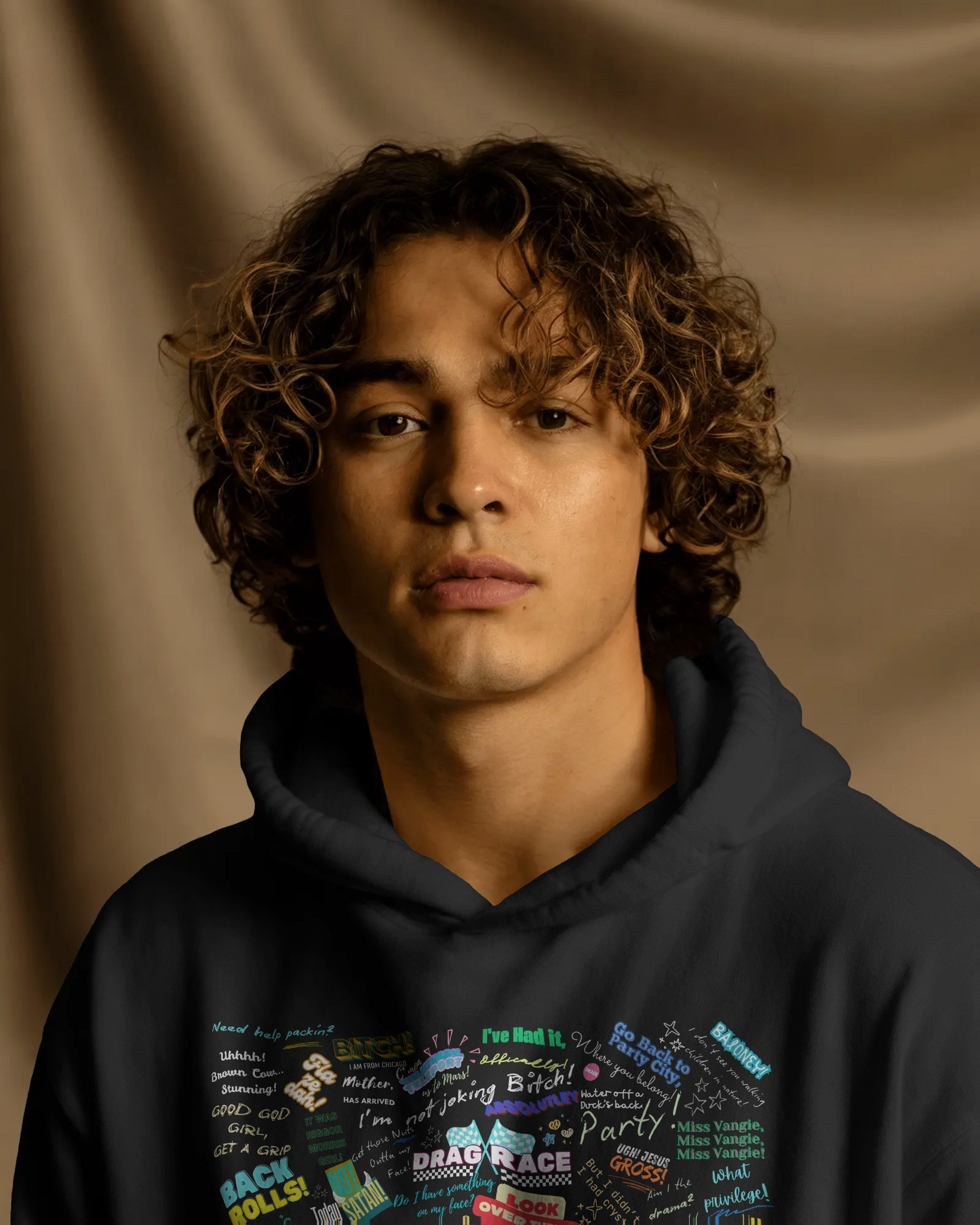 Person wearing a dark hoodie with colorful text design against a brown background  Drag race, Rupaul, Rupaul's Drag Race UK, LGBT, Queer Culture, Gay, Drag Queen