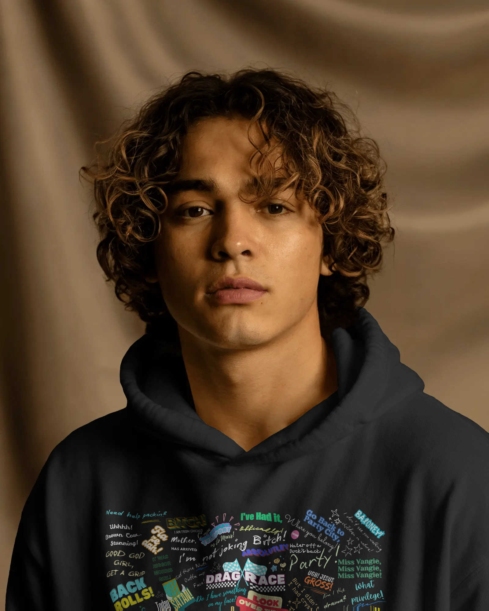 Person wearing a dark hoodie with colorful text design against a brown background  Drag race, Rupaul, Rupaul's Drag Race UK, LGBT, Queer Culture, Gay, Drag Queen