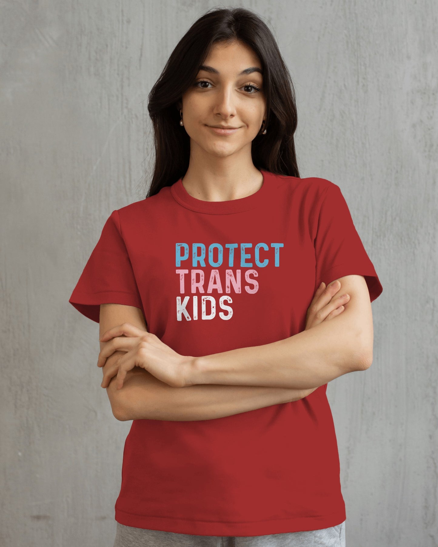 Person wearing a red t-shirt with 'PROTECT TRANS KIDS' text on a gray background LGBTQIA+, Queer, Trans rights