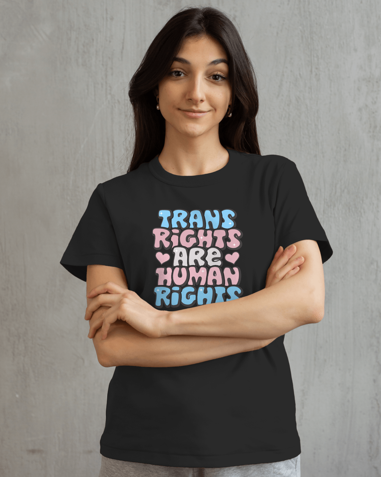 Person wearing a black t-shirt with 'Trans Rights Are Human Rights' text in colorful letters on a gray background LGBTQIA+, Queer, Trans rights