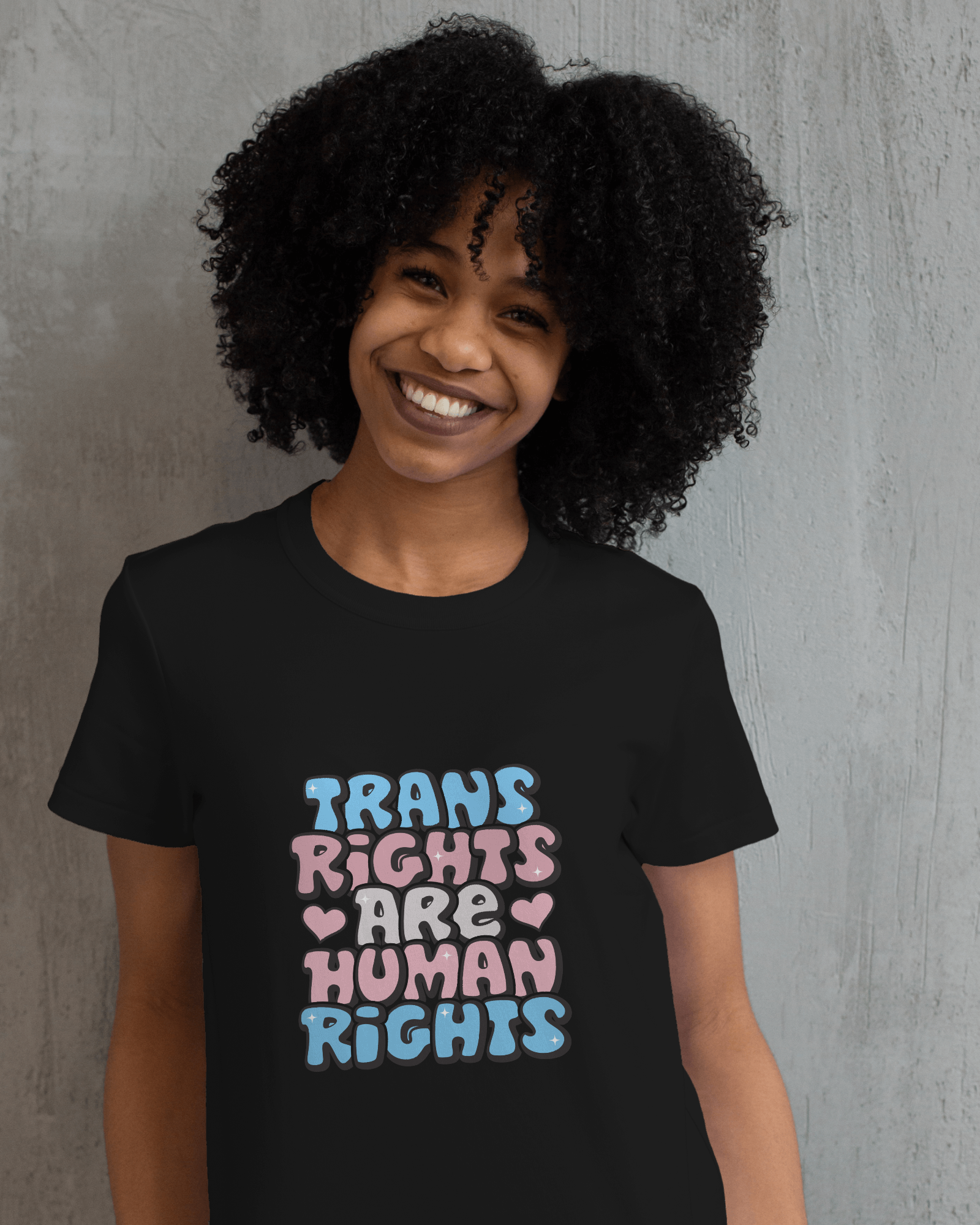Person wearing a black t-shirt with 'Trans Rights Are Human Rights' text in colorful letters against a gray background LGBTQIA+, Queer, Trans rights