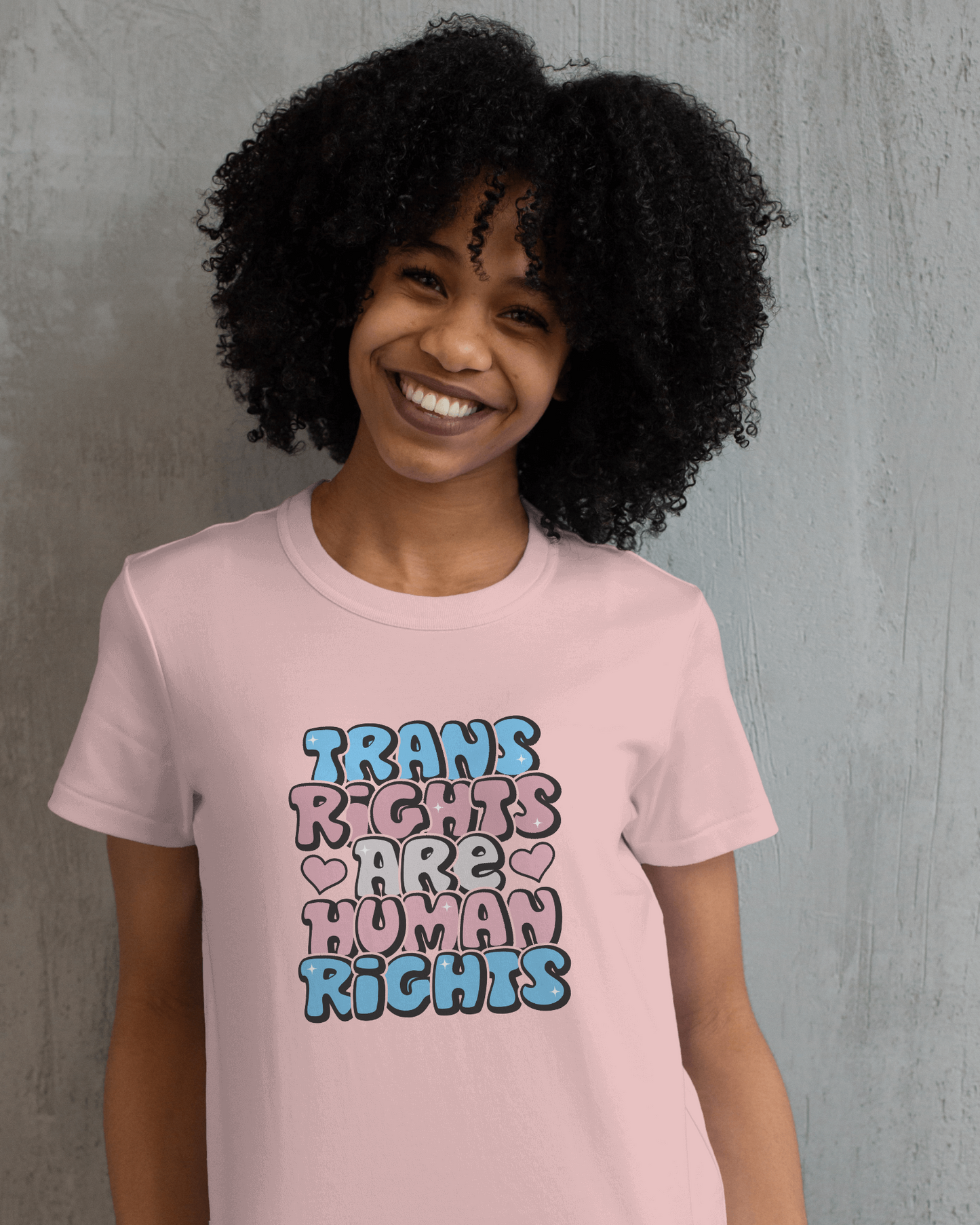 Person wearing a pink t-shirt with 'Trans Rights Are Human Rights' text on a gray background LGBTQIA+, Queer, Trans rights