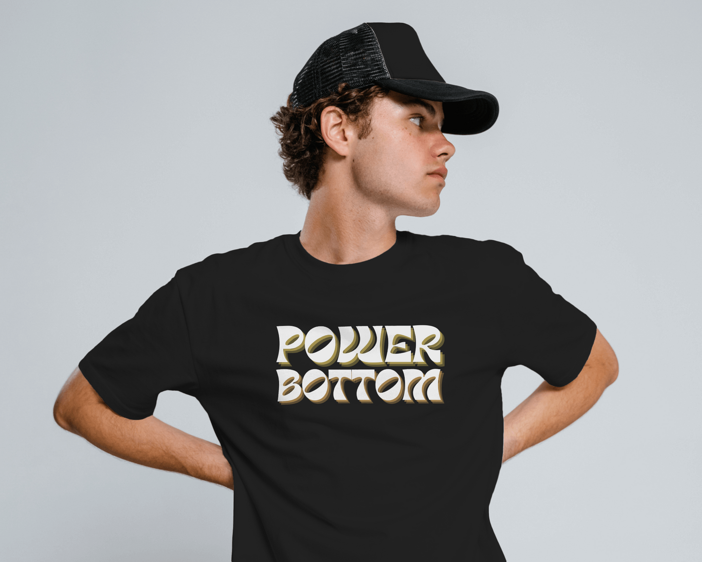 Person wearing a black t-shirt with 'POWDER BOTTOM' text and a black cap on a gray backgroundKink, LGBTQIA+, Queer Sub Dom 
