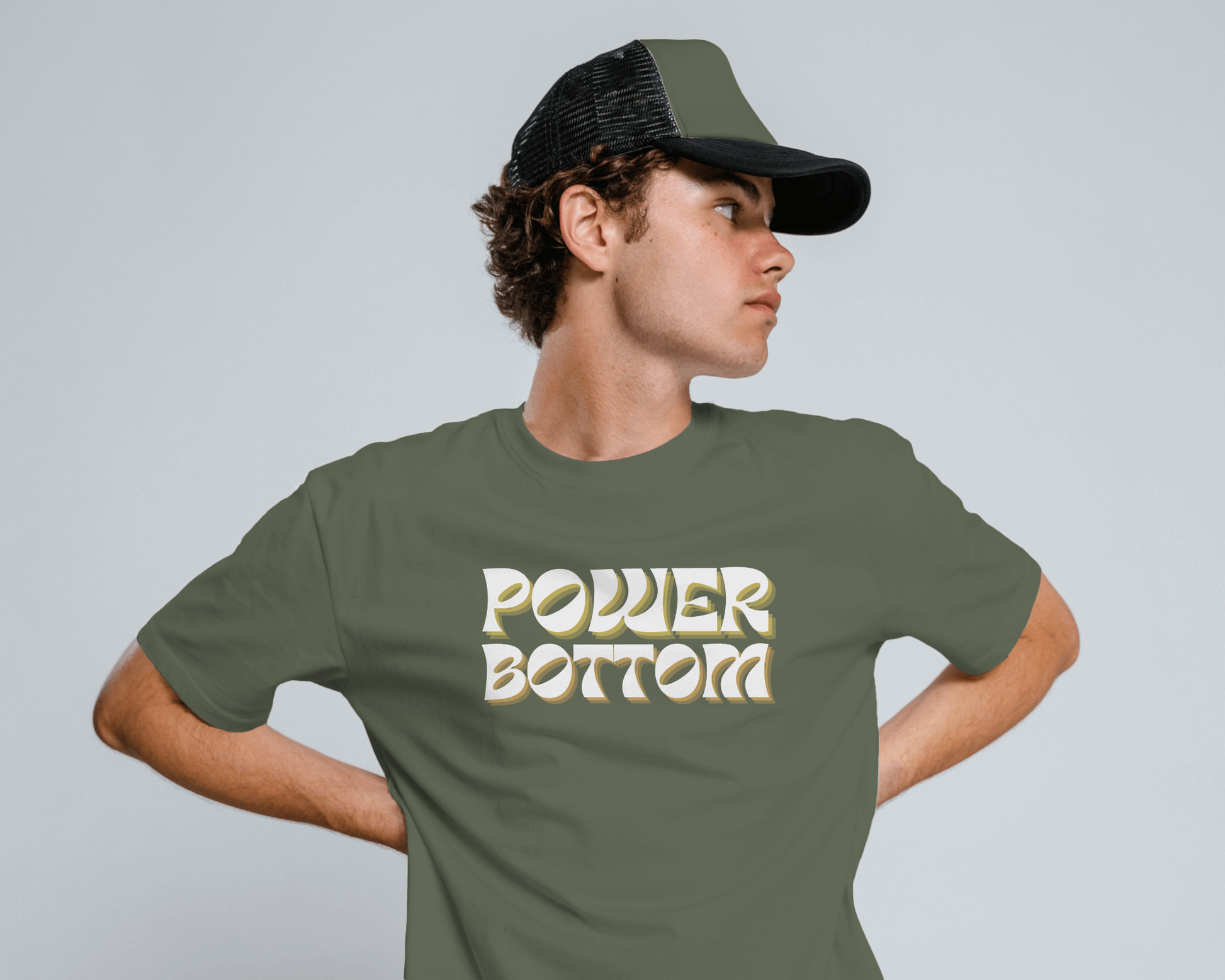 Person wearing a green t-shirt with 'POWDER BOTTOM' text and a cap on a gray backgroundKink, LGBTQIA+, Queer Sub Dom 