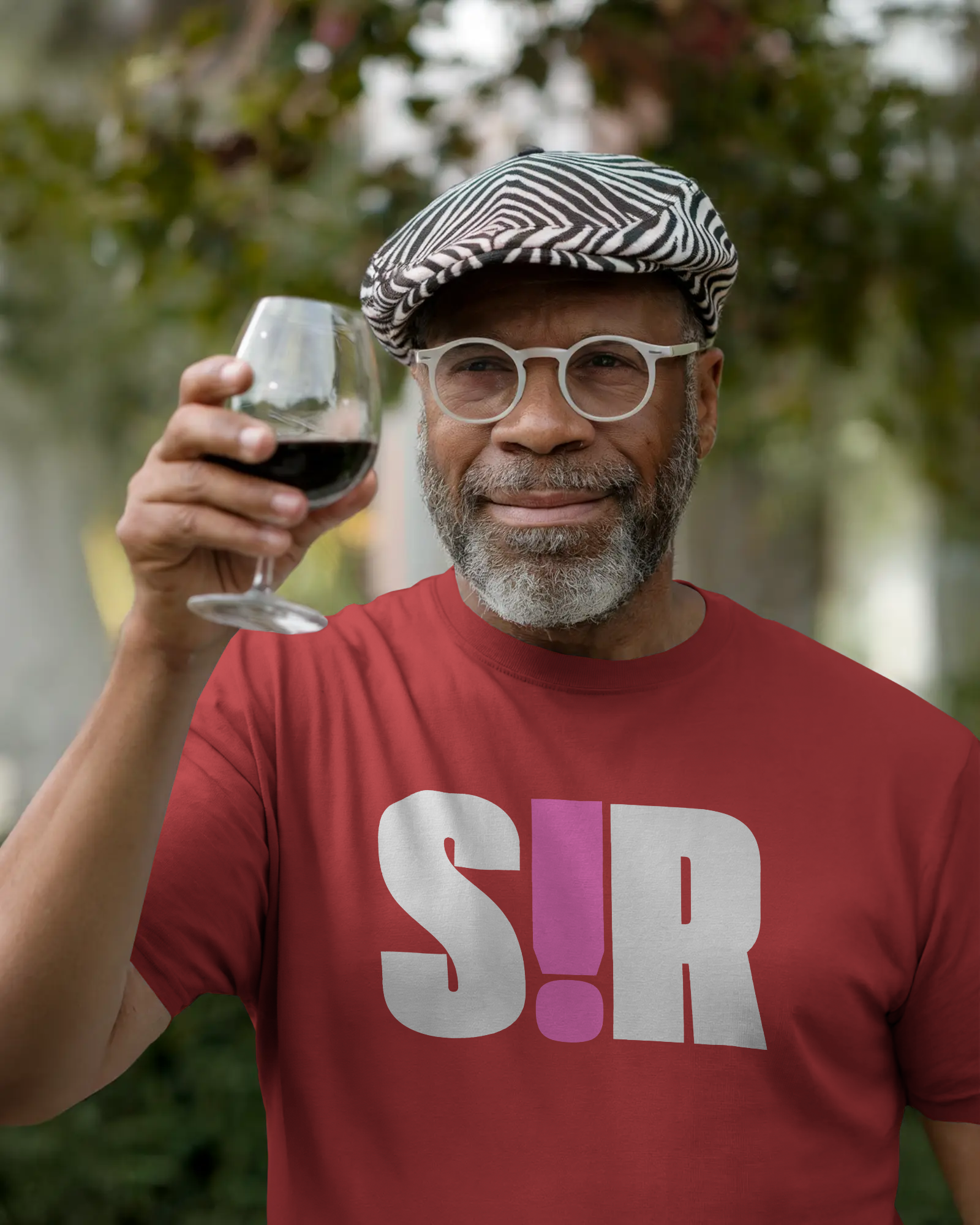 Man in a red shirt with 'S!R' holding a glass of wine outdoors Kink, LGBTQIA+, Queer Sub Dom