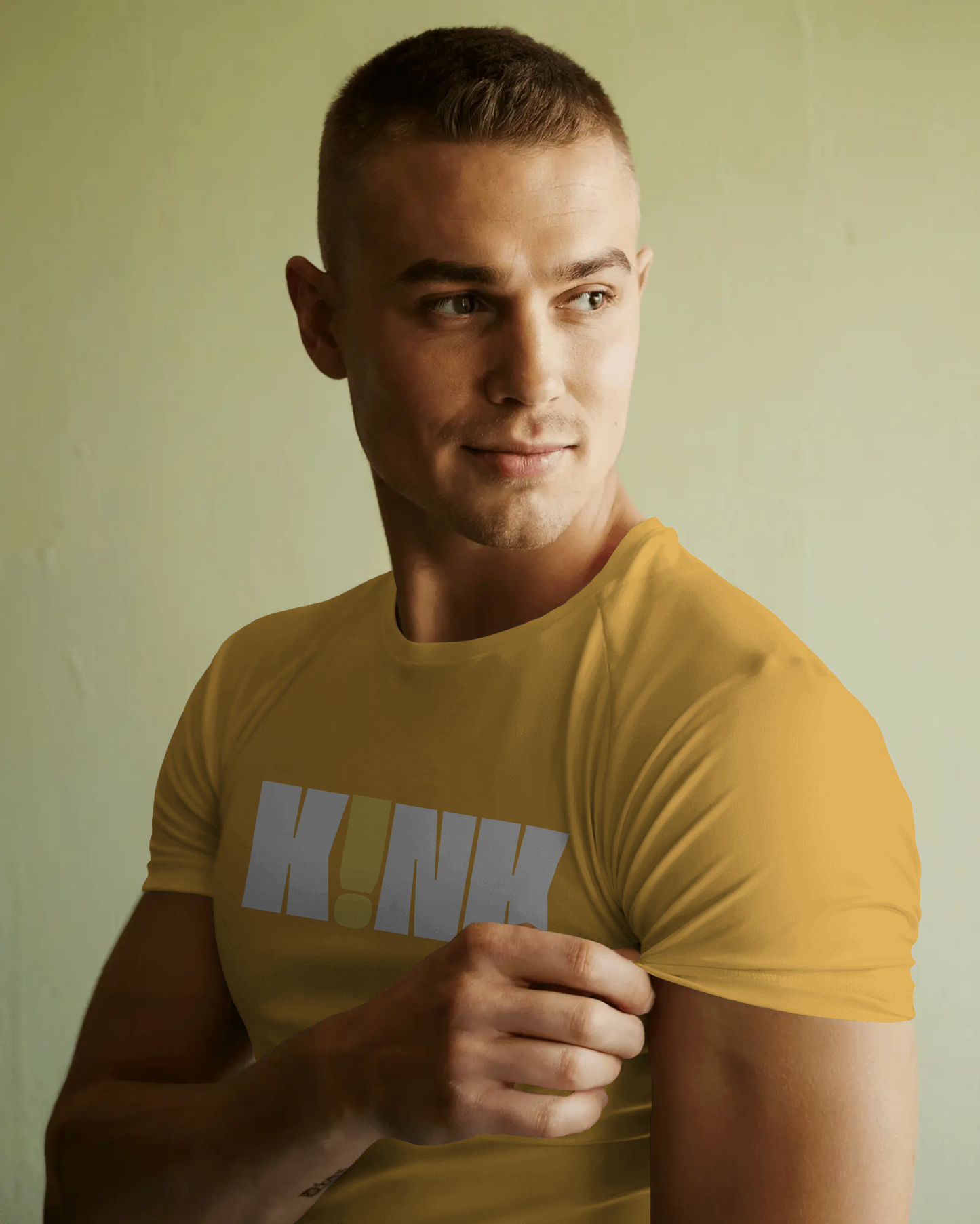 Man wearing a mustard yellow t-shirt with 'HINK' printed on it against a plain background   Kink, LGBTQIA+, Queer