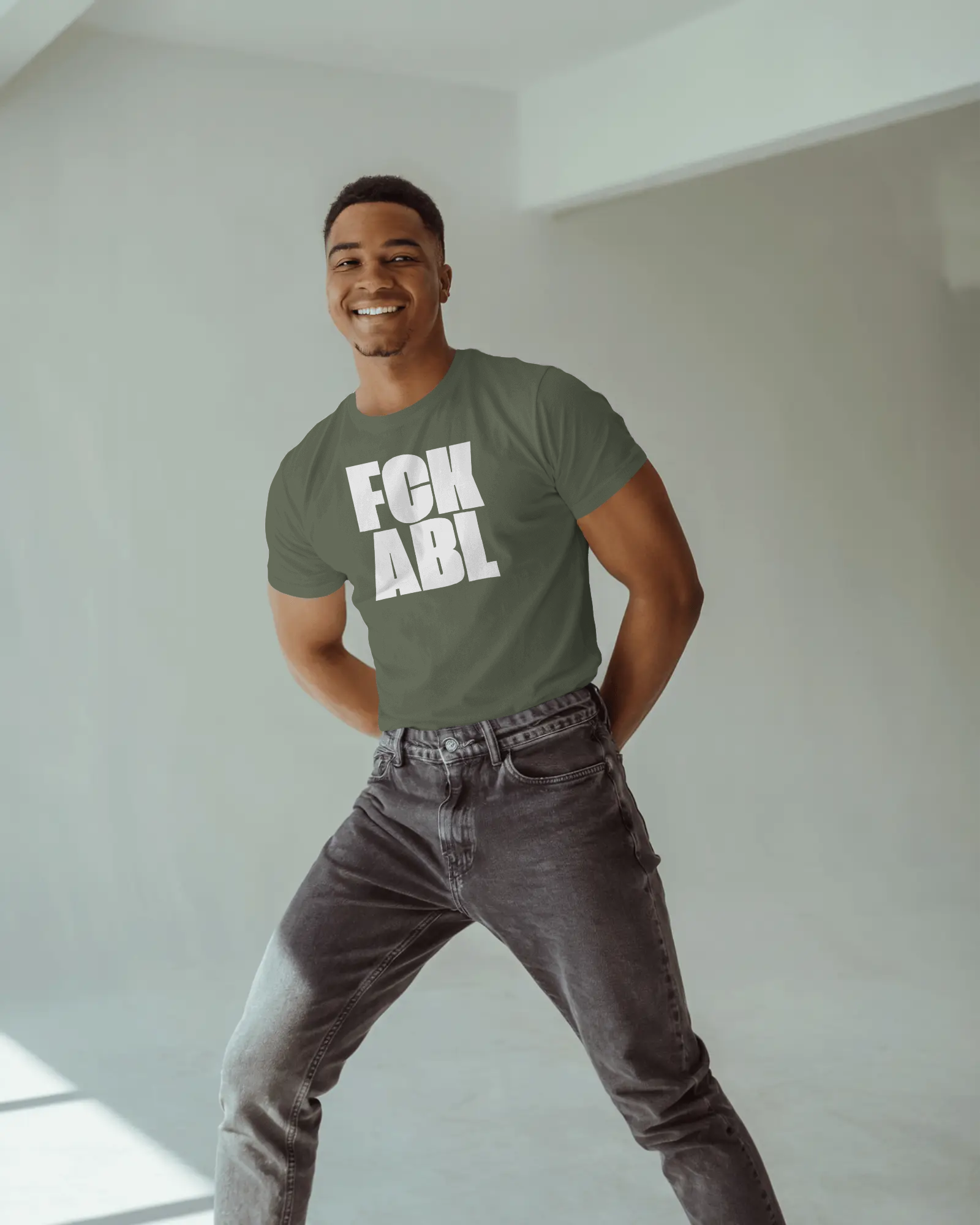 Man wearing a green t-shirt with 'FCK ABL' text in a minimal indoor setting