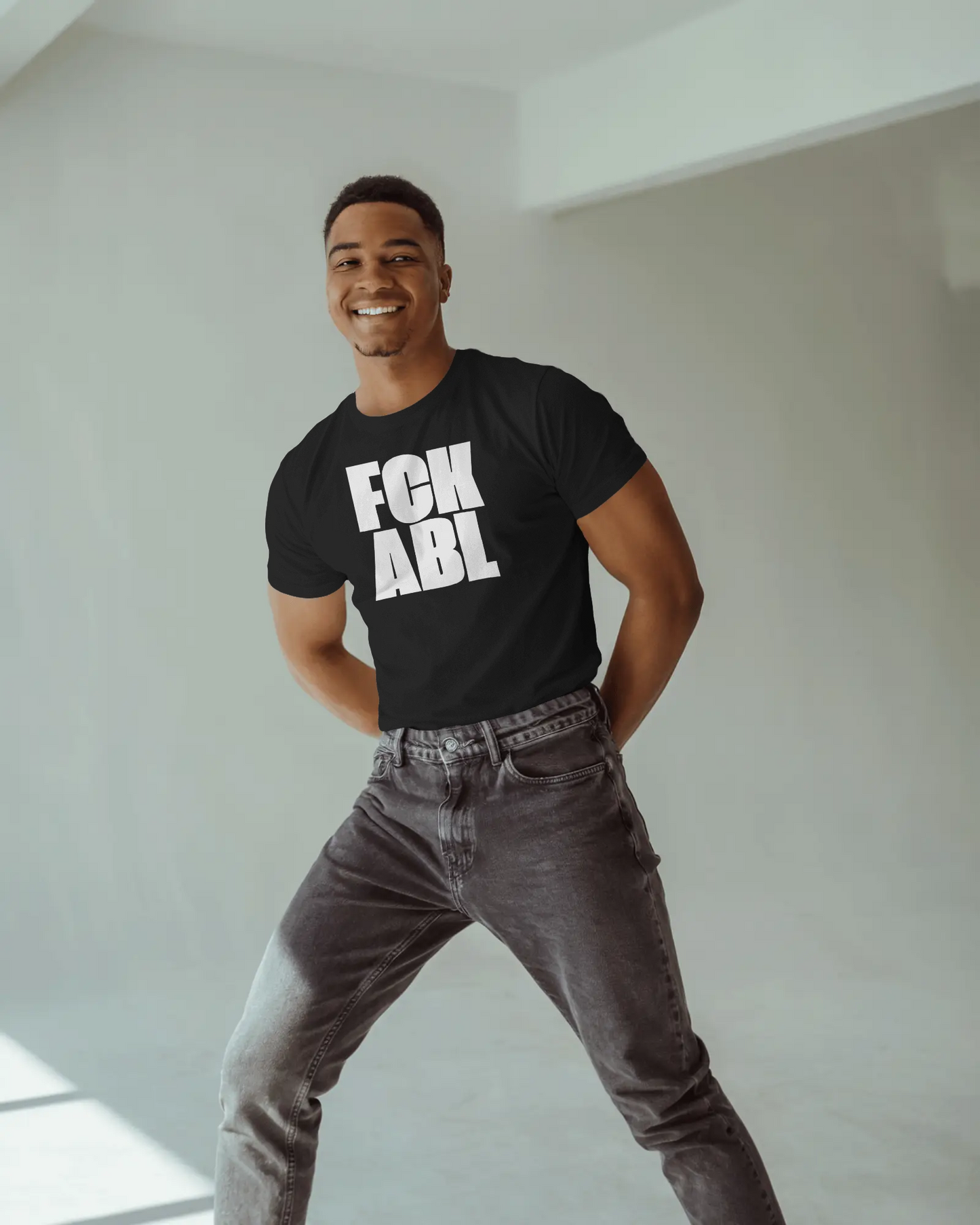 Man wearing a black t-shirt with 'FCK ABL' text, standing against a plain background