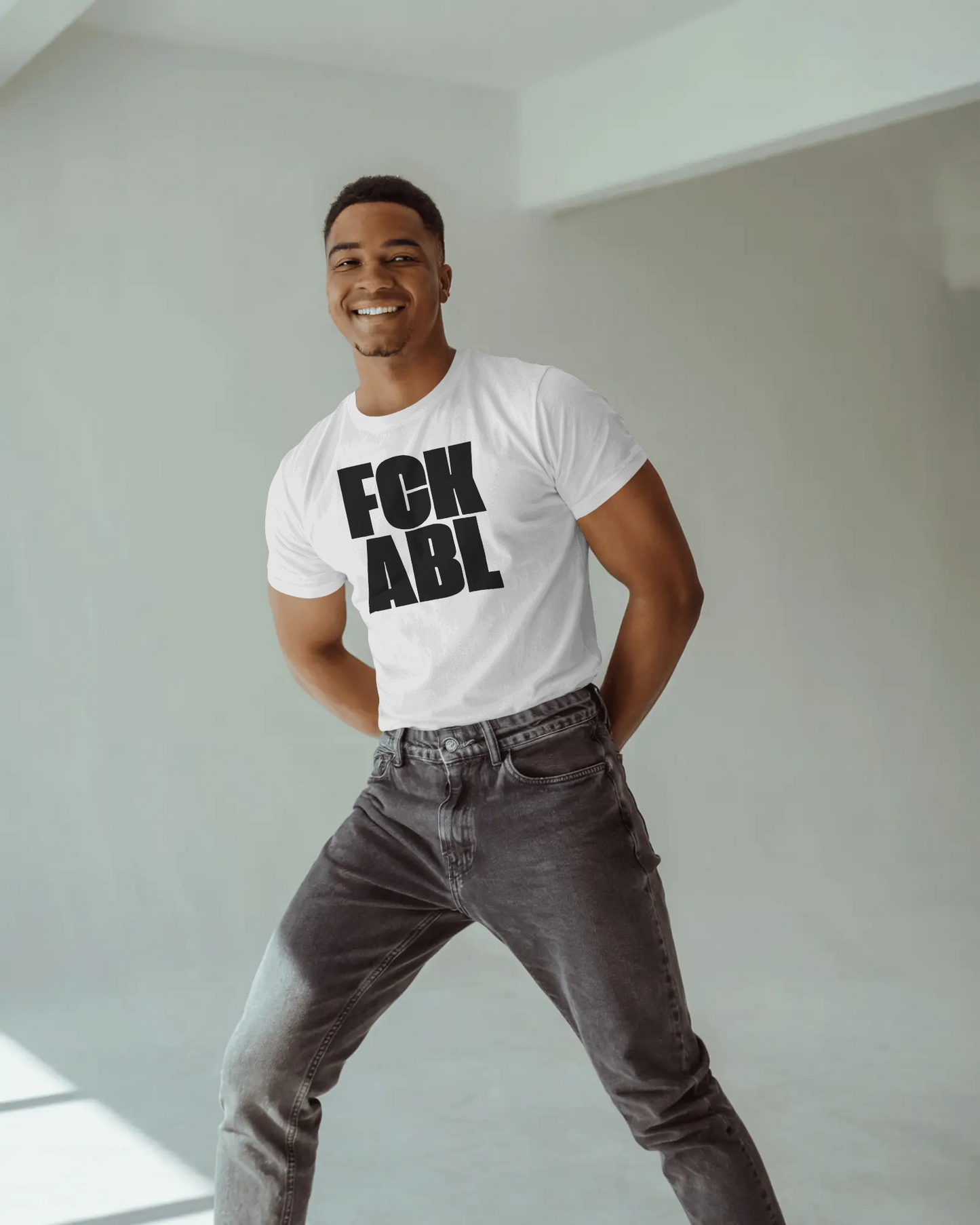 Man wearing a white t-shirt with 'FOK ABL' text in a minimal indoor setting