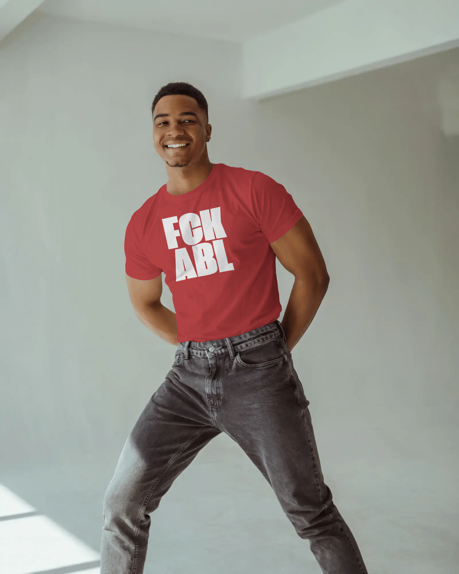 Man wearing a red t-shirt with 'FCK ABL' text in a minimal indoor setting