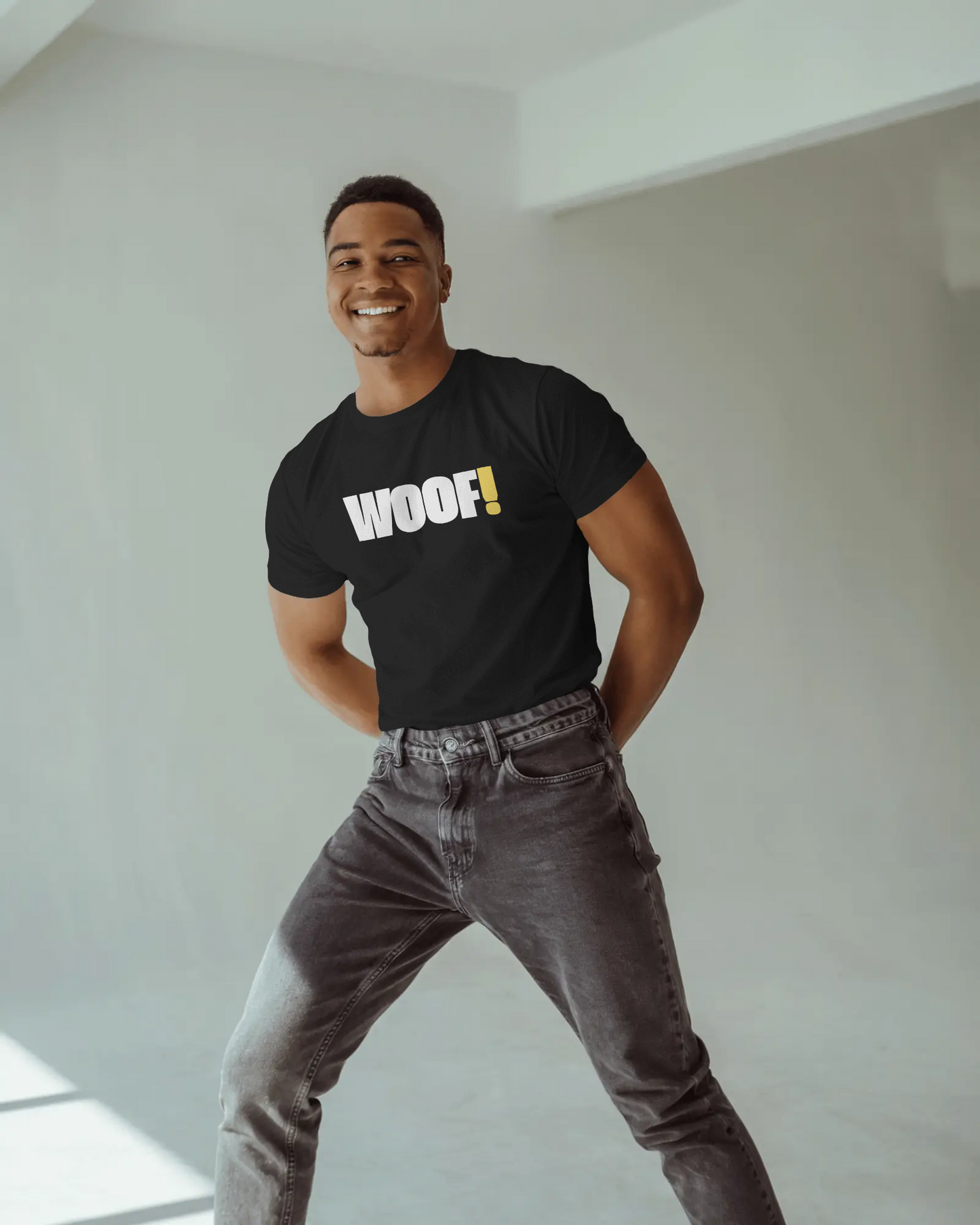 Man wearing a black t-shirt with 'WOOF!' text against a dark background LGBTQIA+ QUEER, Kink Positive
