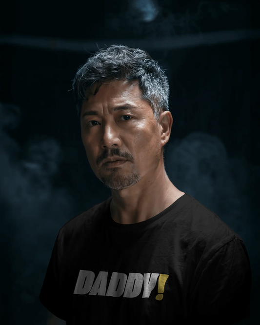 Man wearing a black t-shirt with 'DADDY!' text against a dark background LGBTQIA+ Kink Positive