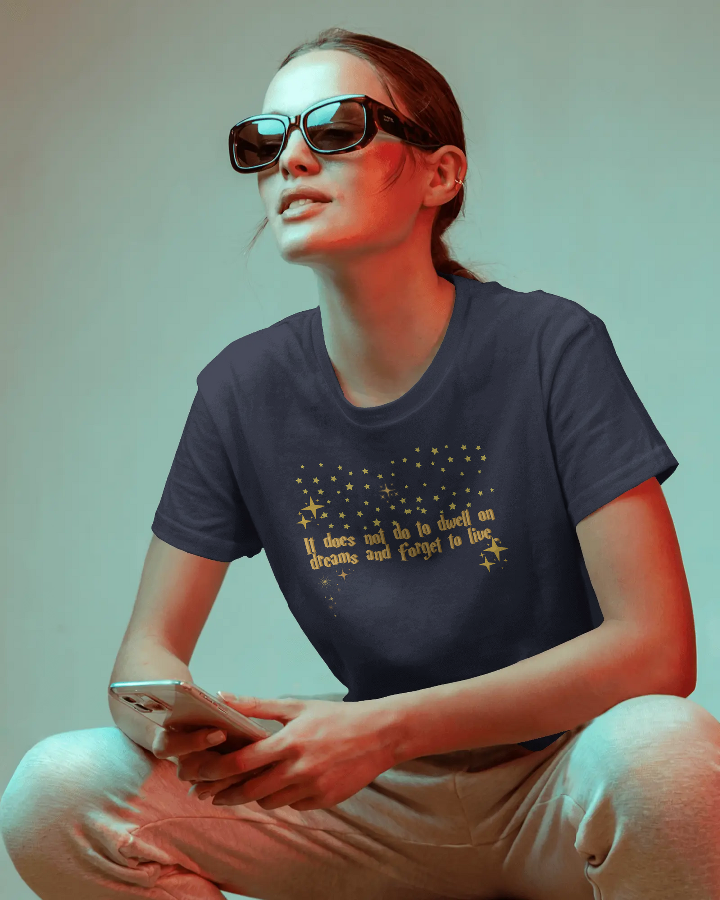 Person wearing a dark blue t-shirt with text and graphics, sitting against a gradient background.Dumbledore quote, harry potter