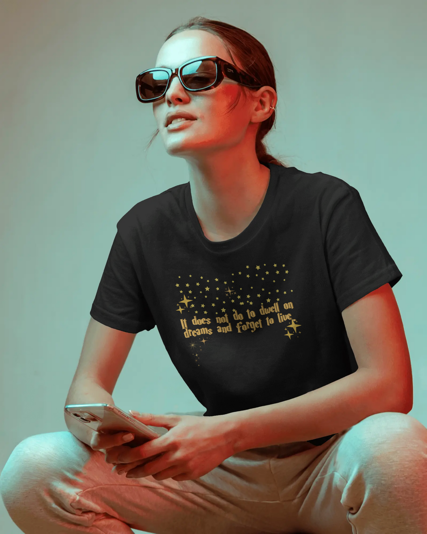 Person wearing a black t-shirt with text and sunglasses, sitting against a plain background, Dumbledore quote, harry potter