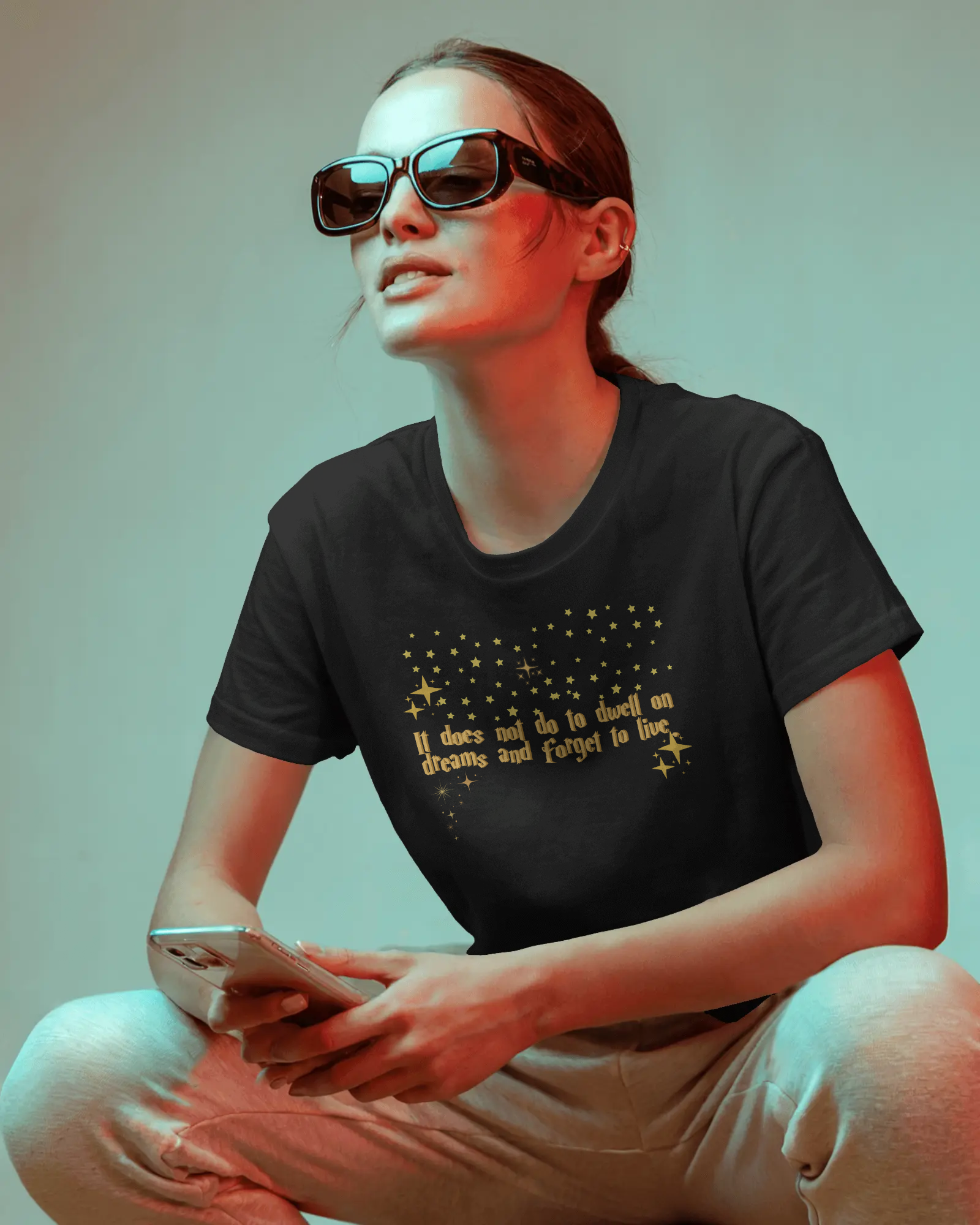 Person wearing a black t-shirt with text and sunglasses, sitting against a plain background, Dumbledore quote, harry potter