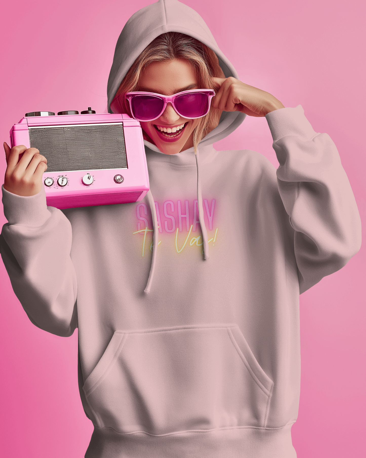 Person wearing a light gray hoodie with text, holding a pink vintage-style radio against a pink background  Drag Race Espana, Drag Race Spain, Rupaul's drag race, Drag queens, LGBT, Queer culture