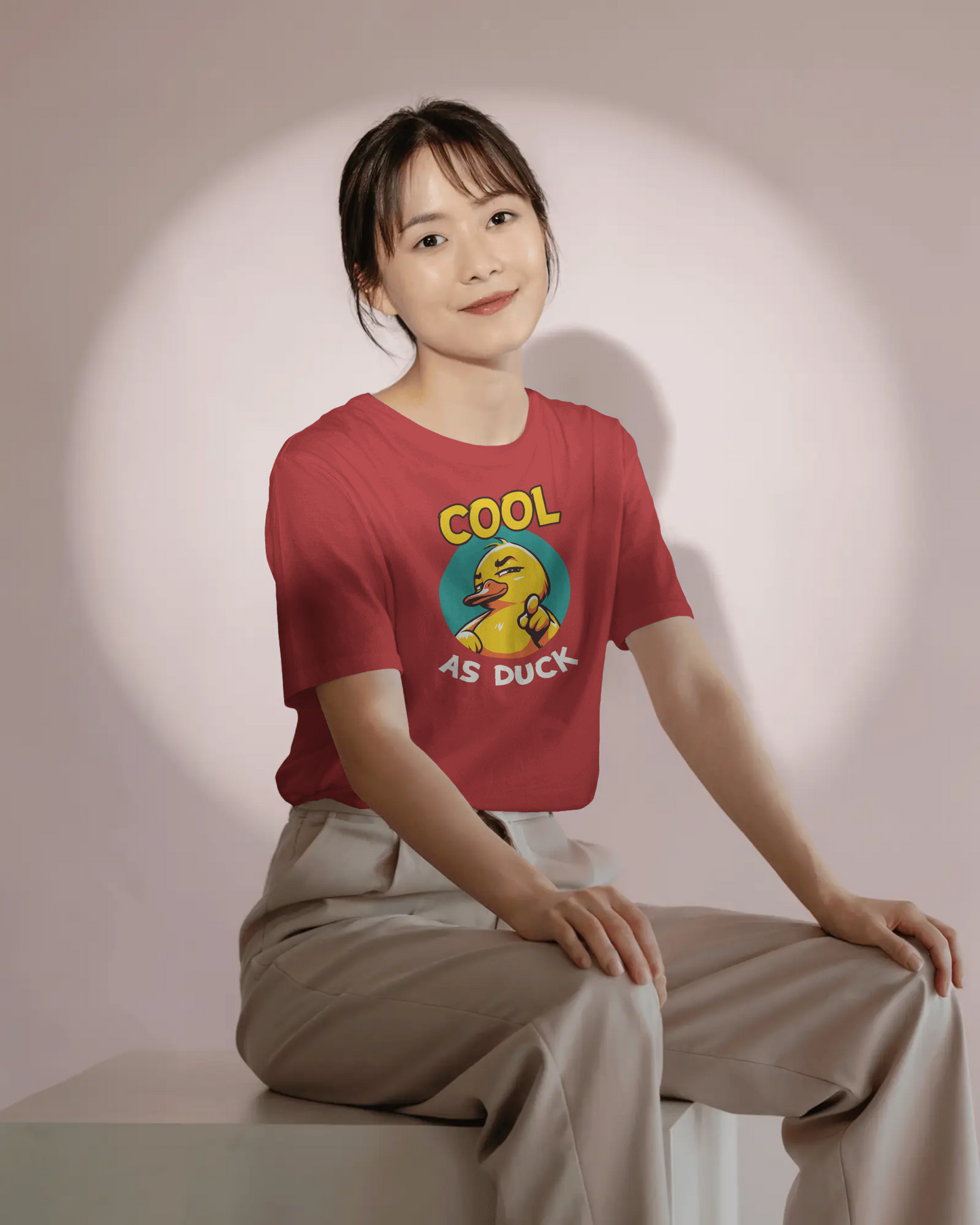 Person wearing a red t-shirt with a graphic design sitting on a white surface.