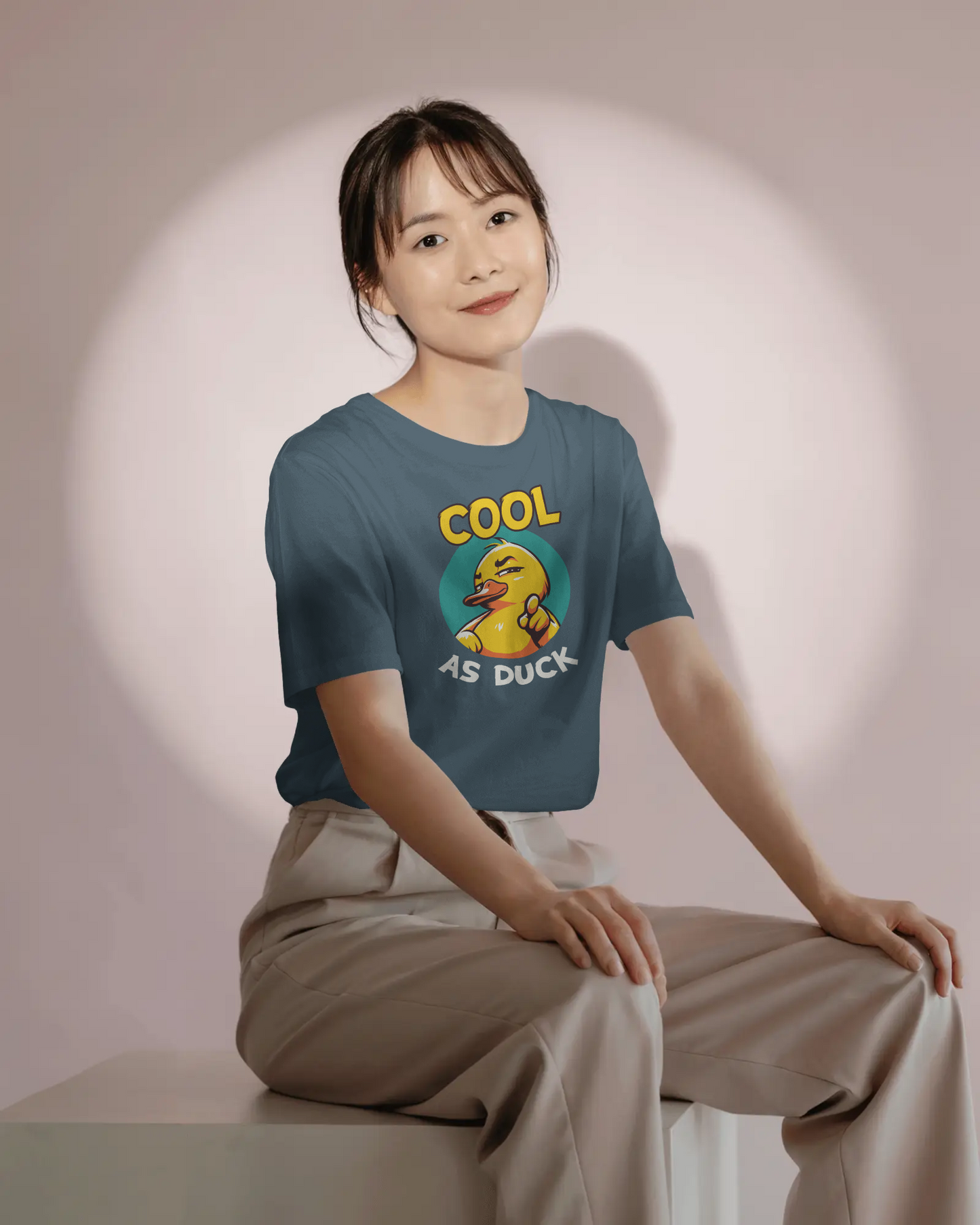 Person wearing a t-shirt with a duck graphic and text, sitting against a plain background