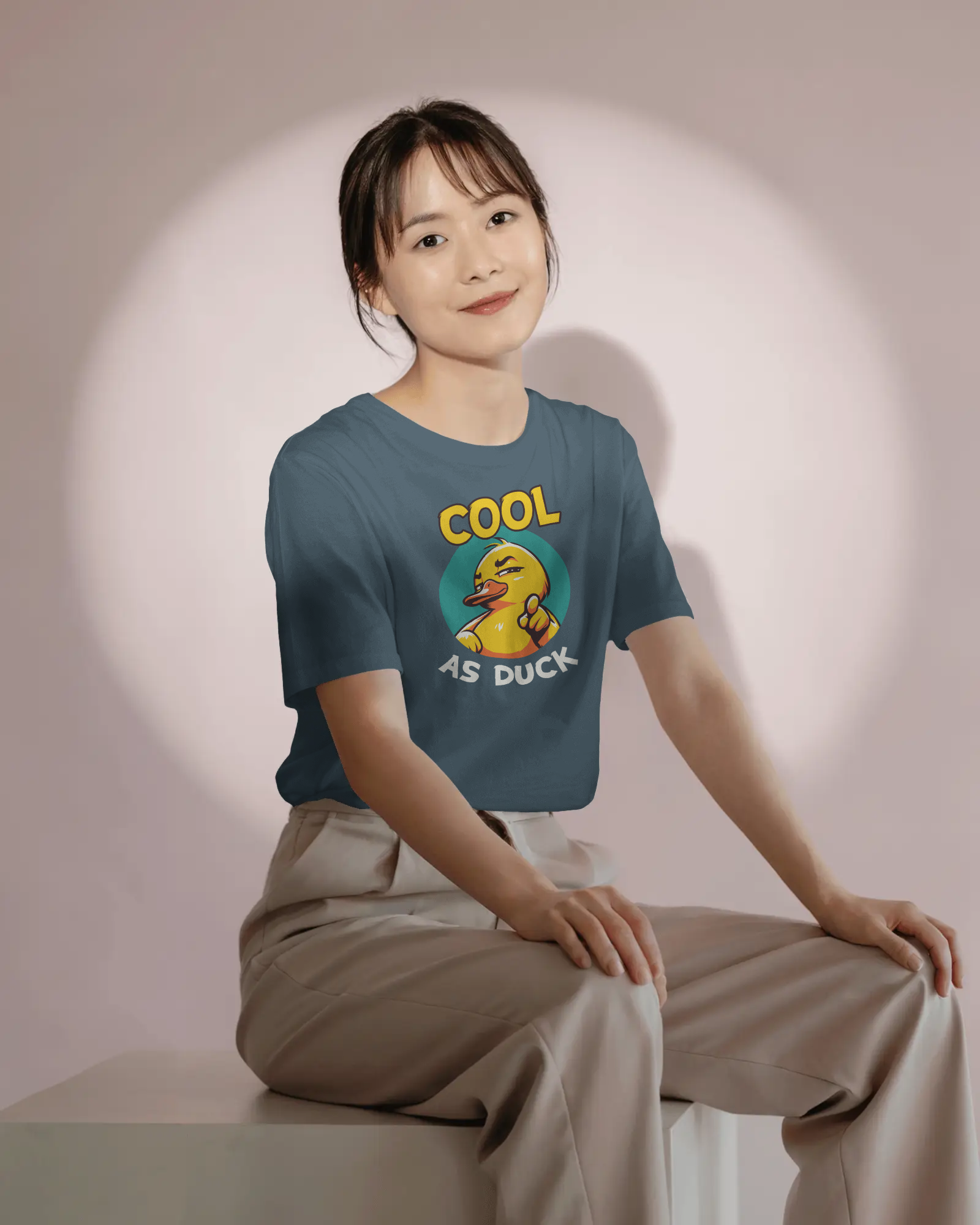 Person wearing a t-shirt with a duck graphic and text, sitting against a plain background