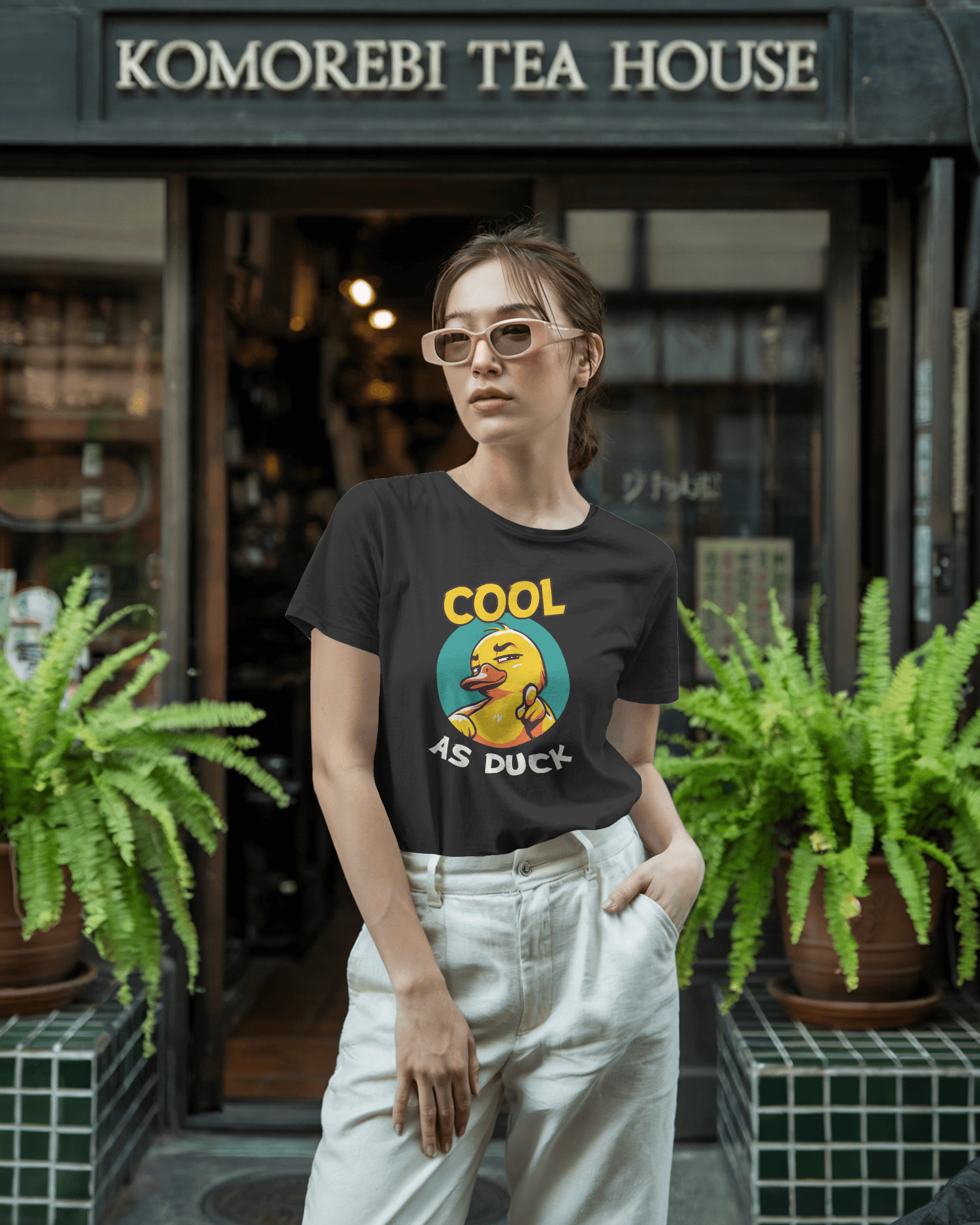Woman wearing a black t-shirt with a graphic design in front of Komorebi Tea House.