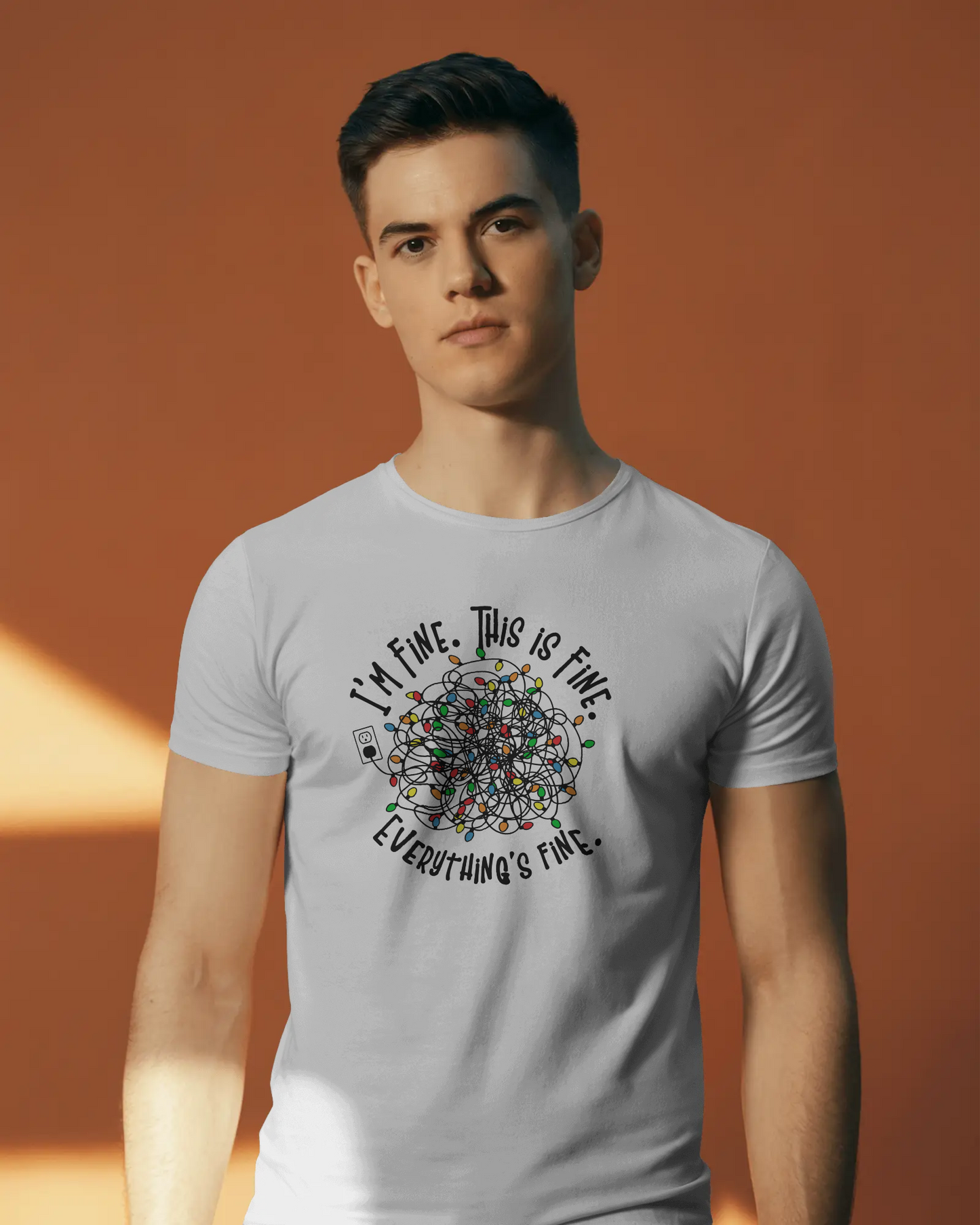 A person wearing a White t-shirt with a colorful design of tangled Christmas Lights and the text "I'm fine, this is fine, everything is fine"