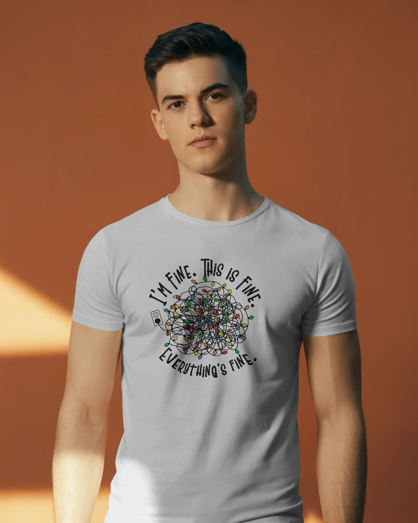 A person wearing a White t-shirt with a colorful design of tangled Christmas Lights and the text "I'm fine, this is fine, everything is fine"