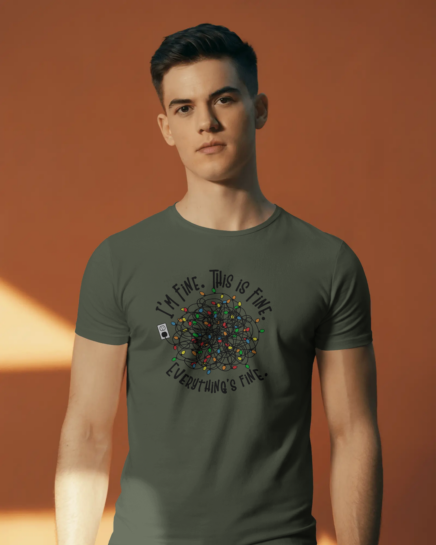 A person wearing a Green t-shirt with a colorful design of tangled Christmas Lights and the text "I'm fine, this is fine, everything is fine"