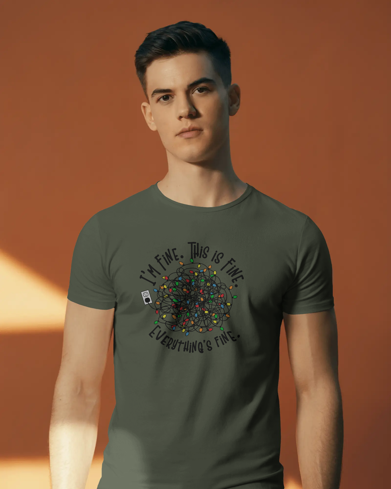 A person wearing a Green t-shirt with a colorful design of tangled Christmas Lights and the text "I'm fine, this is fine, everything is fine"