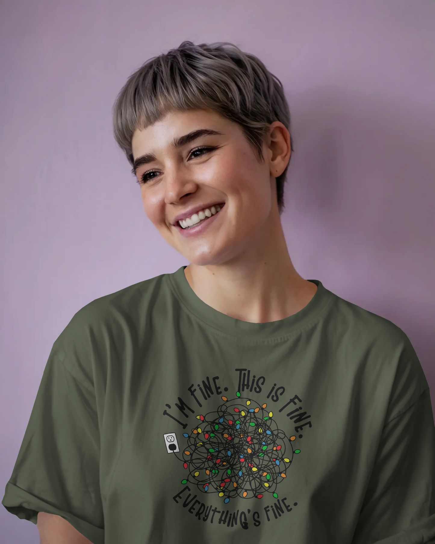 A person wearing a Green t-shirt with a colorful design of tangled Christmas Lights and the text "I'm fine, this is fine, everything is fine"