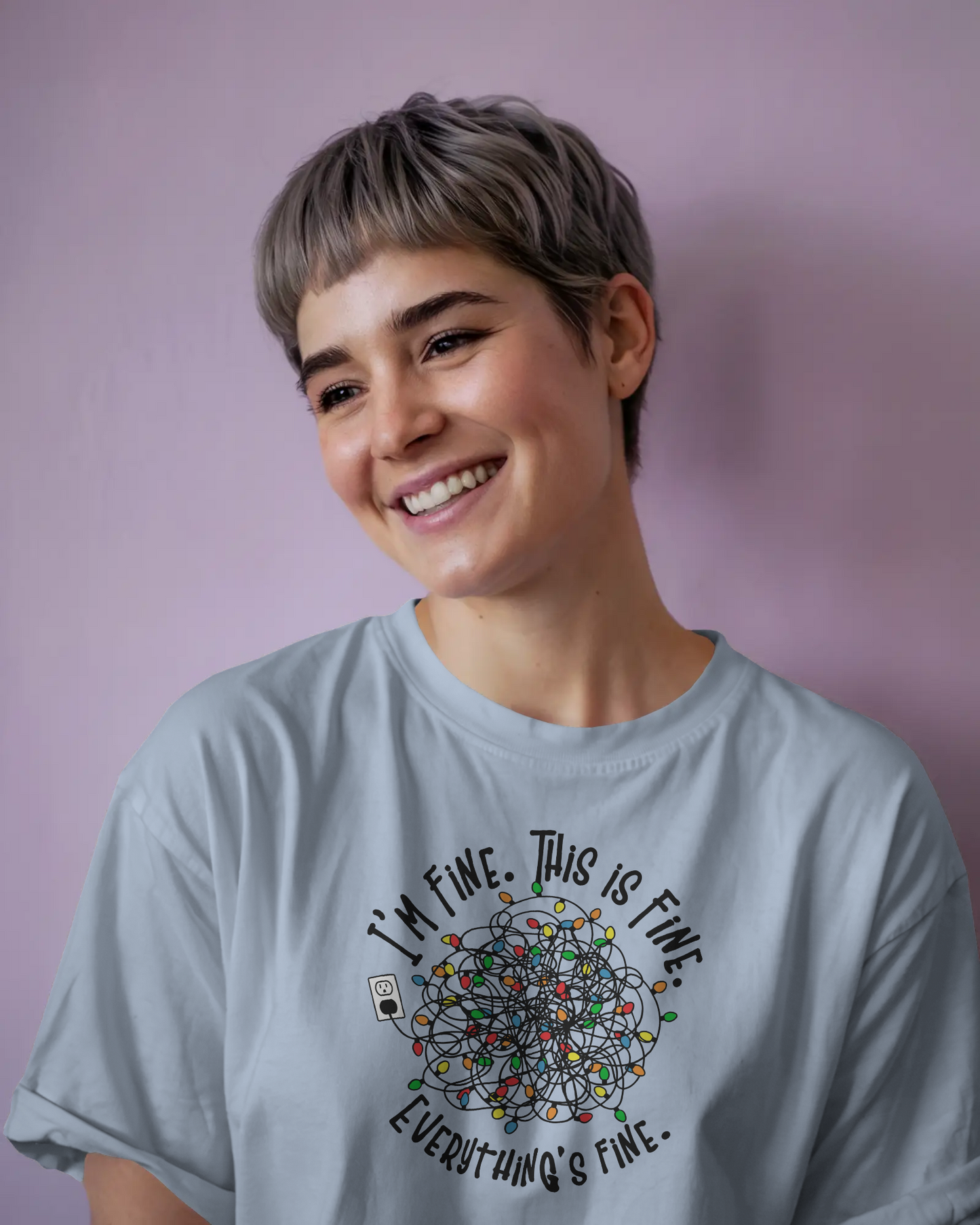 A person wearing a baby blue t-shirt with a colorful design of tangled Christmas Lights and the text "I'm fine, this is fine, everything is fine"