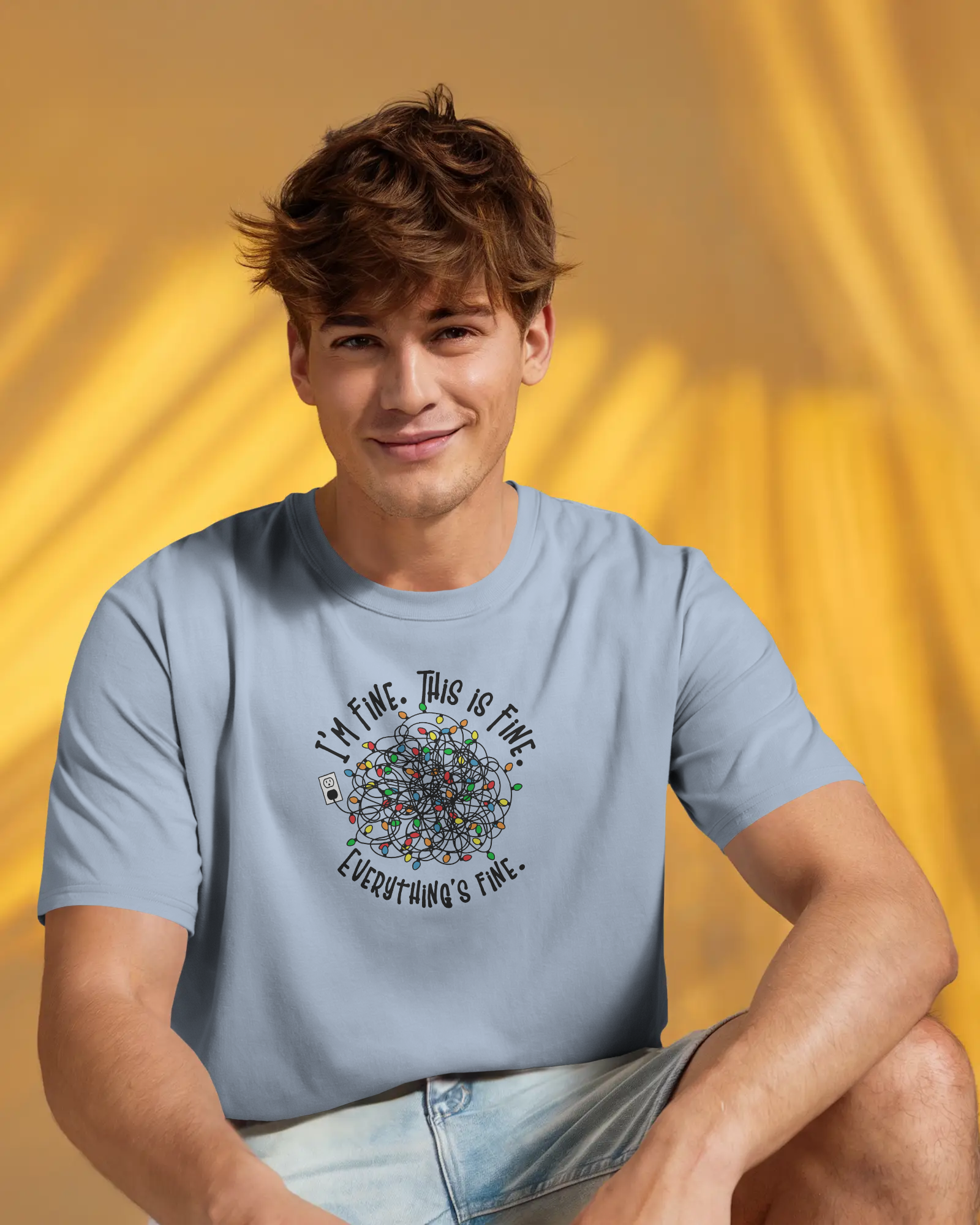 A person wearing a baby blue t-shirt with a colorful design of tangled Christmas Lights and the text "I'm fine, this is fine, everything is fine"