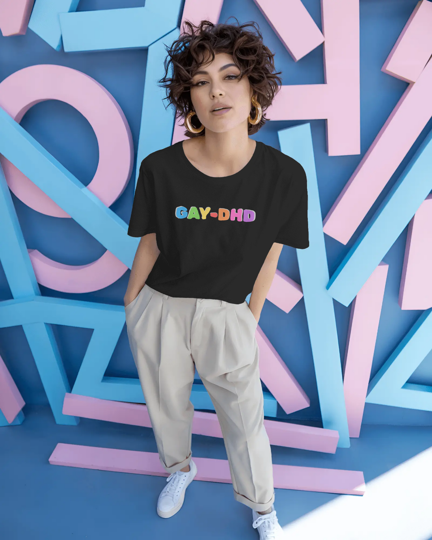 Person wearing a black t-shirt with colorful text in front of a colorful geometric background