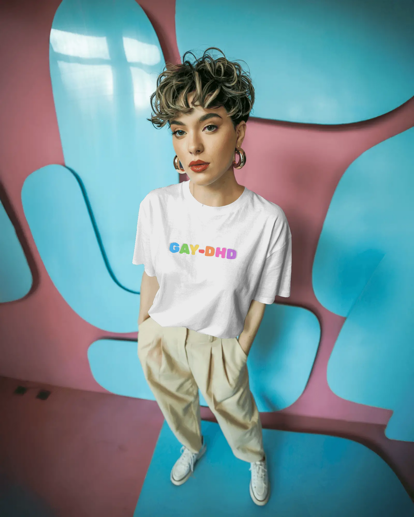 Person wearing a white t-shirt with 'GAY-DHD' text in colorful letters against a vibrant, abstract background.