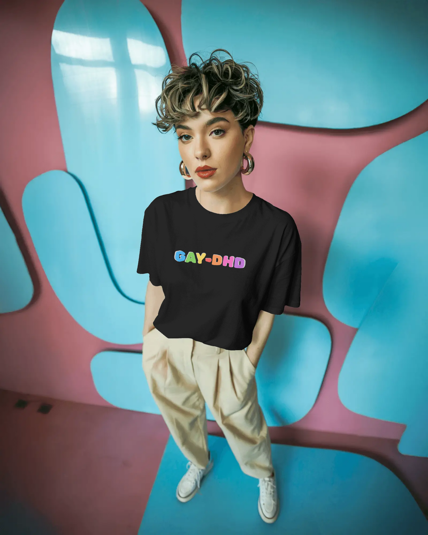 Person wearing a black t-shirt with 'GAY-DHD' text in colorful letters against a vibrant, abstract background.