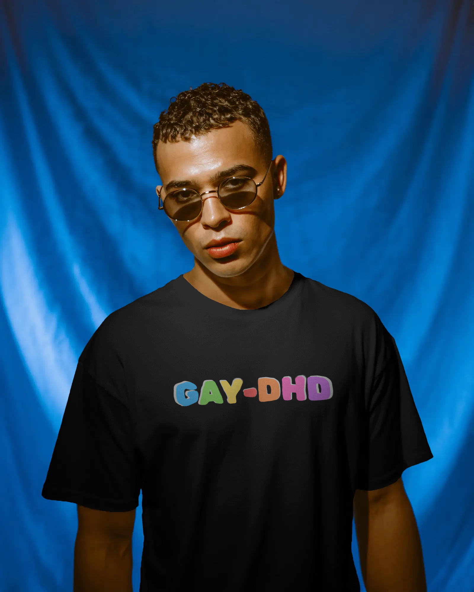 Person wearing a black t-shirt with 'GAY-DHD' in colorful letters against a blue background