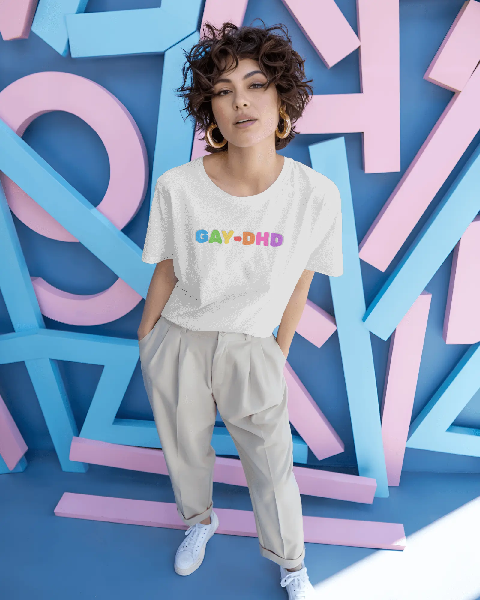 Person wearing a white t-shirt with colorful text standing against a vibrant, abstract background.
