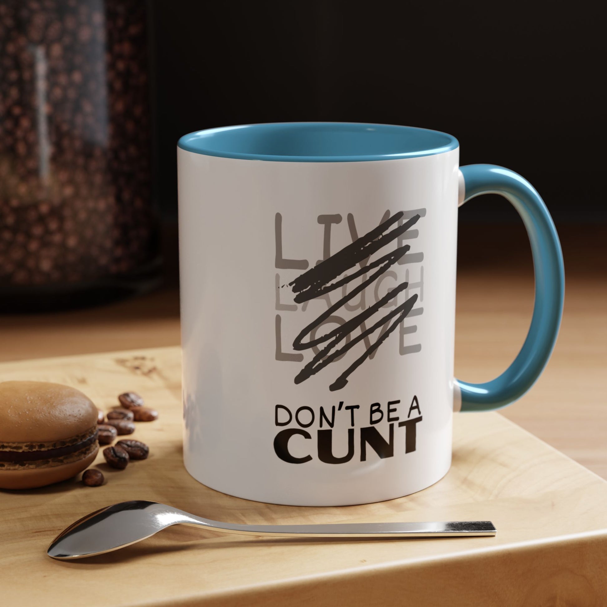 Mug with text on a wooden surface with coffee beans and a spoon